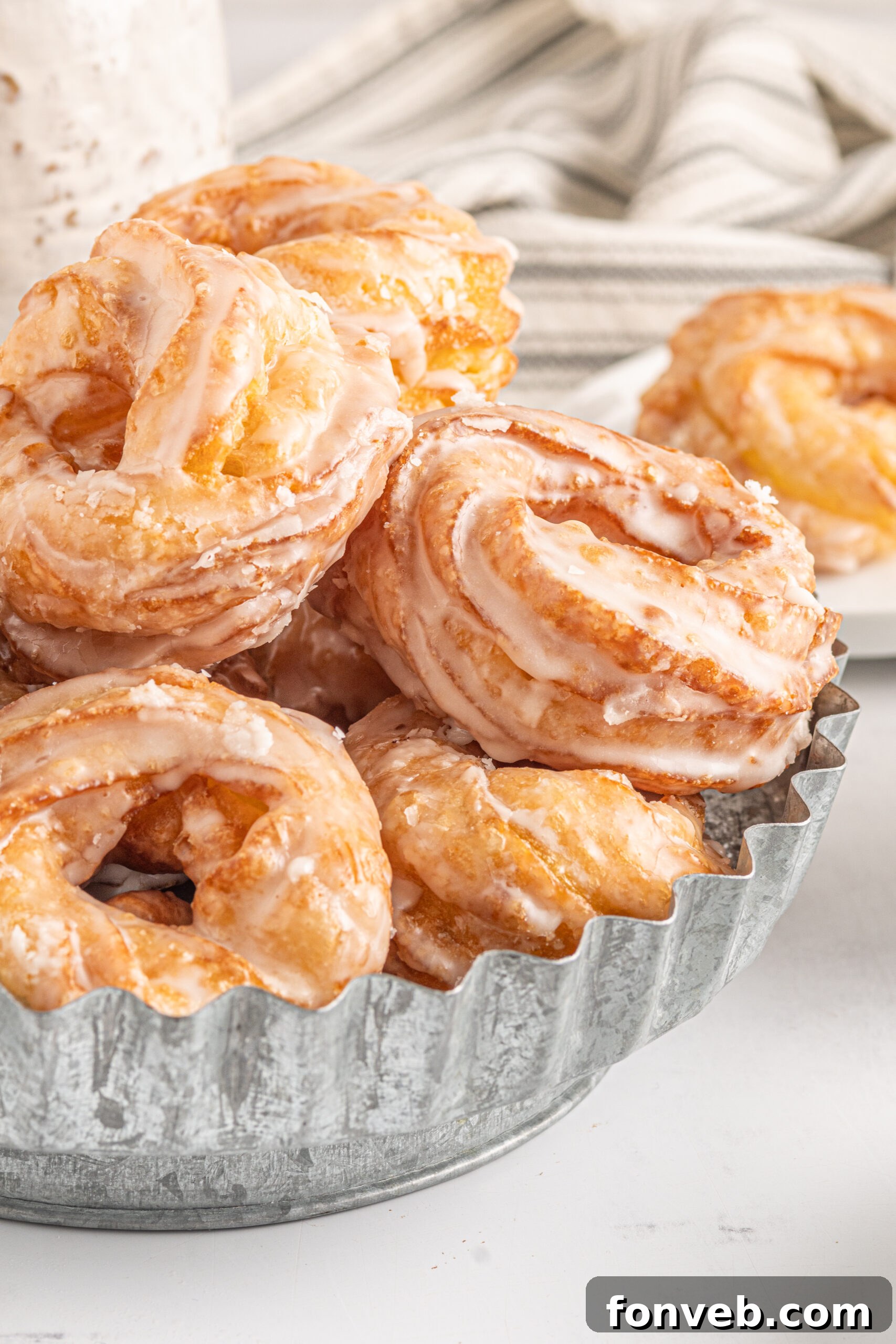 Up close view of French Crullers stacked on a silver serving tray.