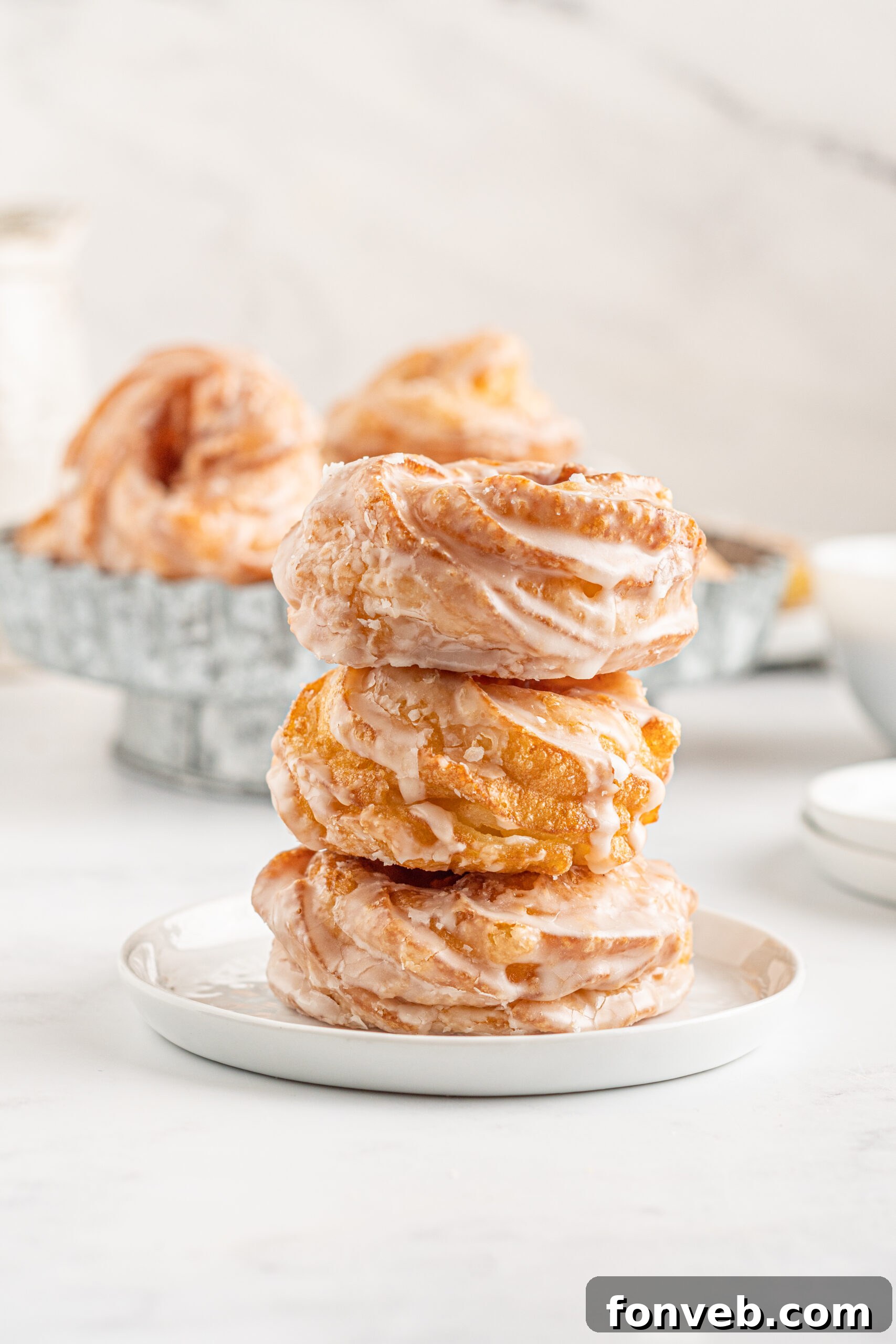 Front view of three French Crullers stacked on a white dish.