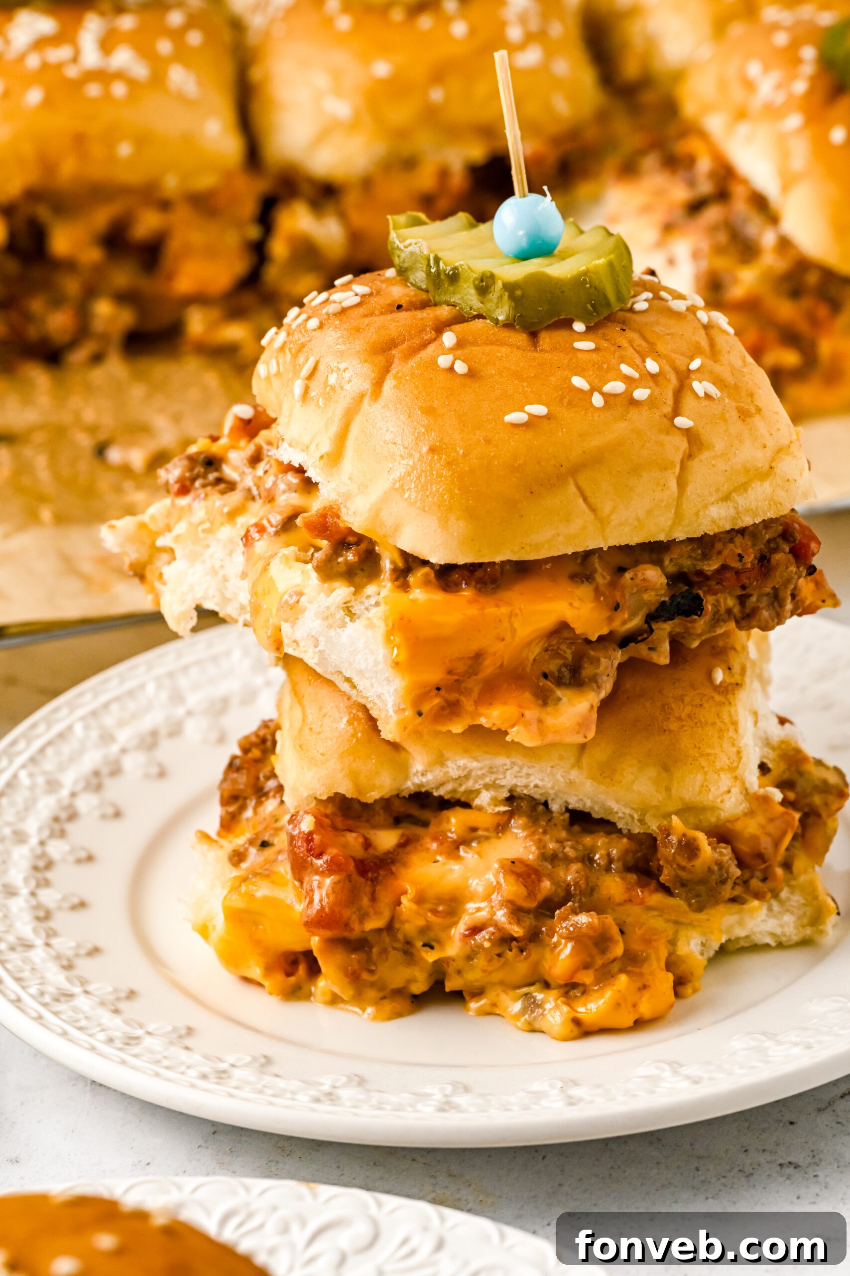 A striking front view of two mouthwatering cheeseburger sliders, artfully stacked on a pristine white dish, showcasing their layers of beef, melted cheese, and fresh toppings.