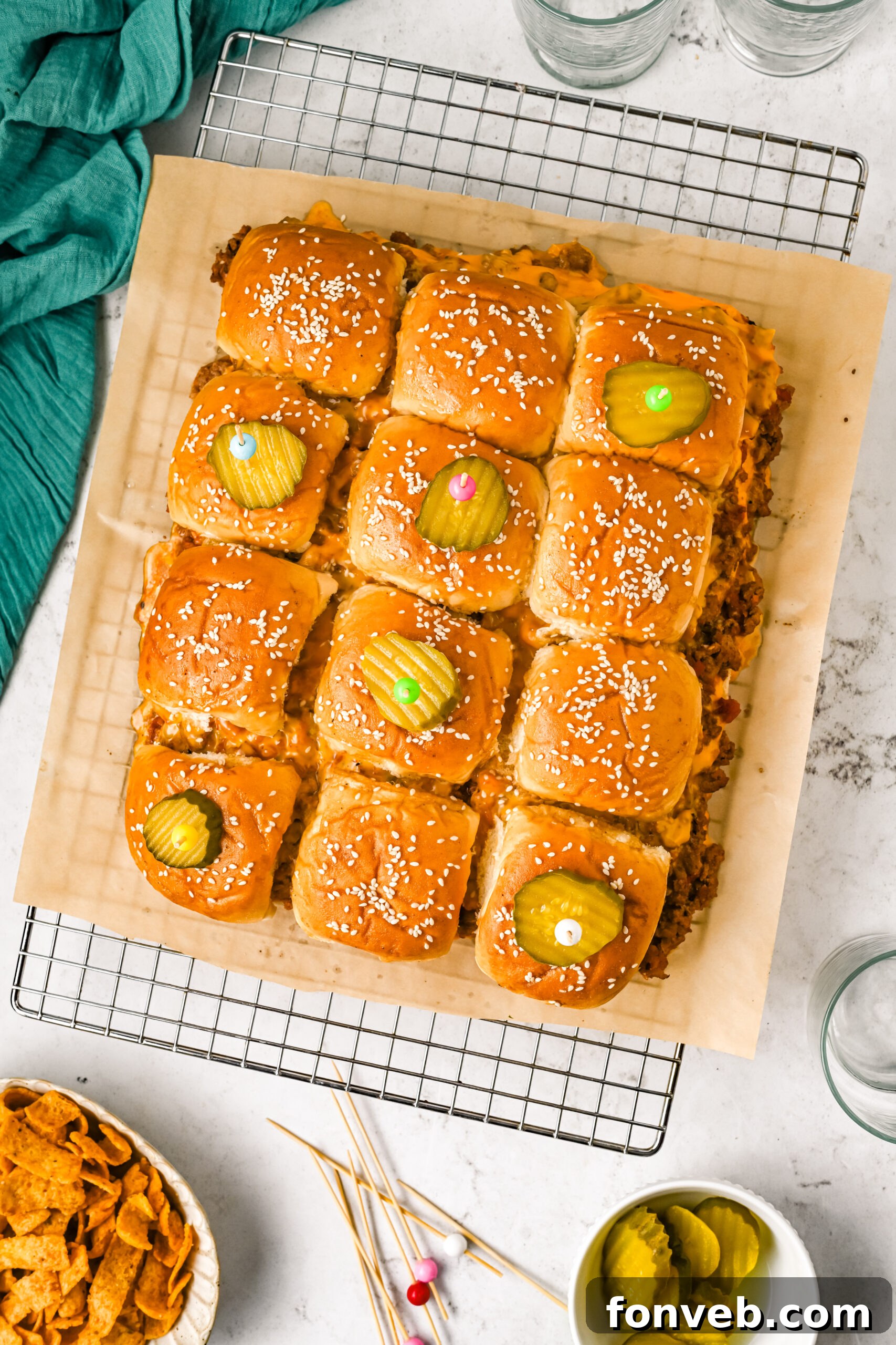 An inviting overhead view of freshly baked cheeseburger sliders, neatly arranged on a wire rack and elegantly garnished with vibrant pickle slices, highlighting their golden-brown buns and melted cheese.