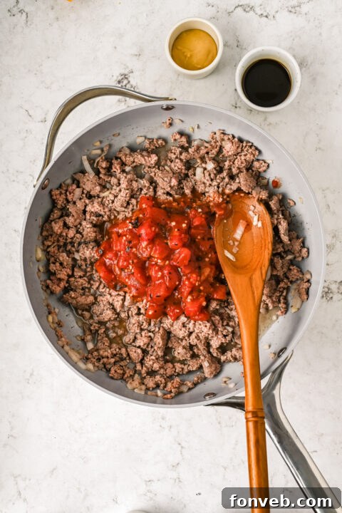 Close-up of diced onions being sautéed in a pan with olive oil, ready for the ground beef.