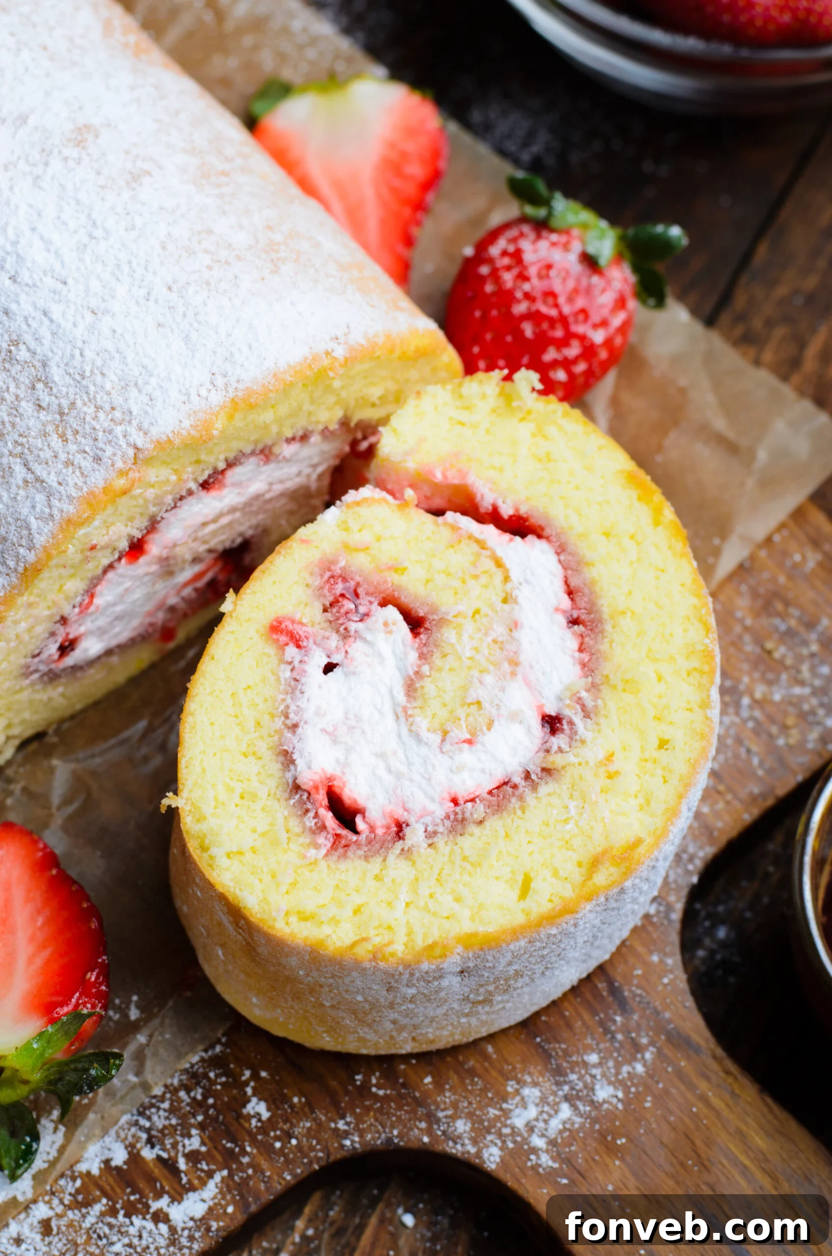 Overhead view of a slice of Strawberries & Cream Cake Roll on a piece of parchment paper.