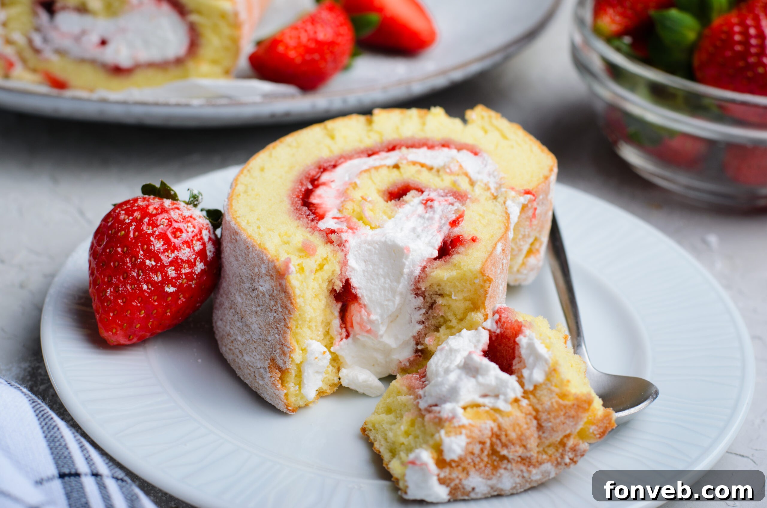 Front view of a slice of Strawberries & Cream Cake Roll with a bite removed