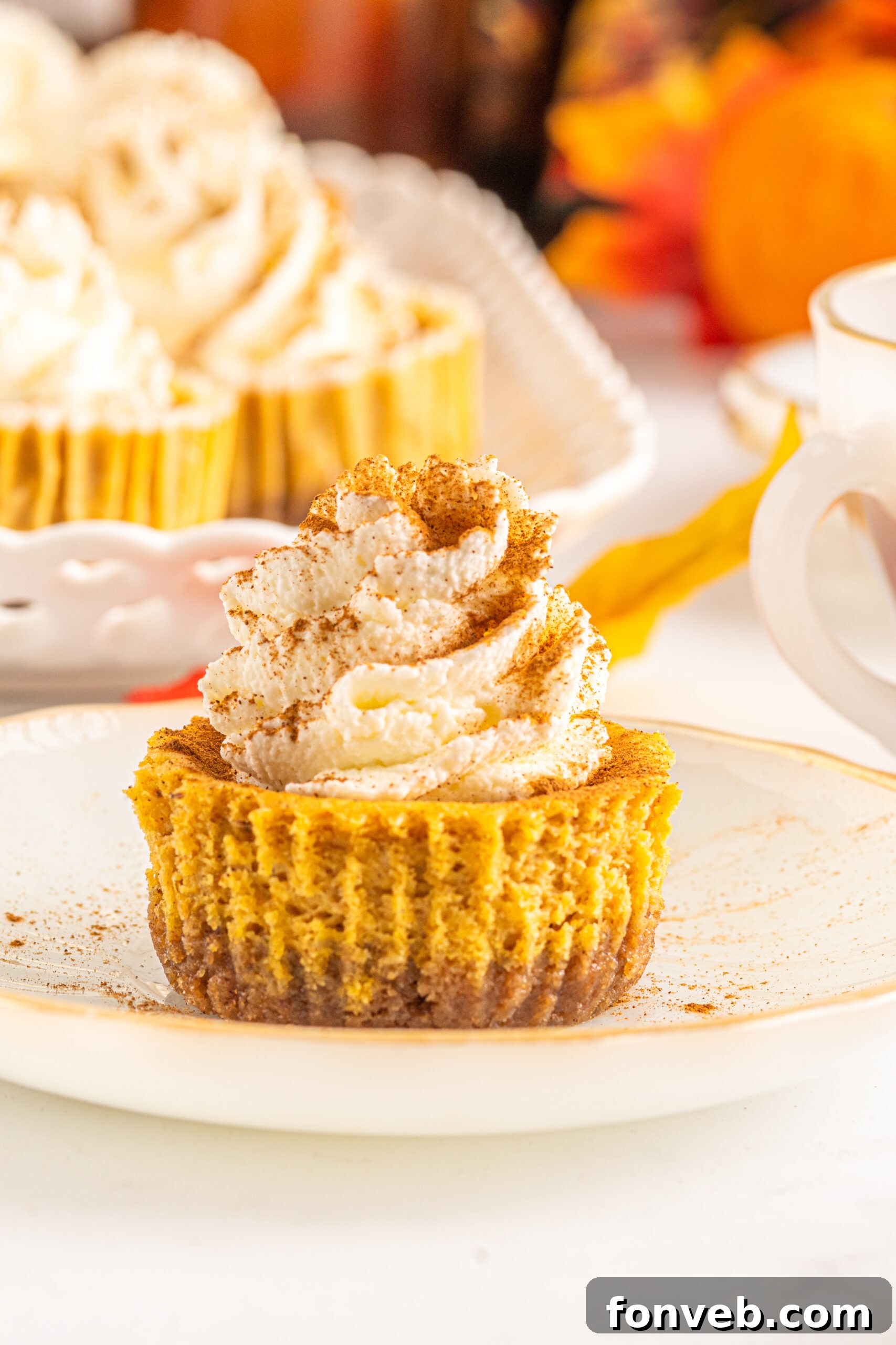 Spiced Fall Cheesecake Bites 17 Front view of a single Mini Pumpkin Cheesecake on a small white dish, ready to be enjoyed.