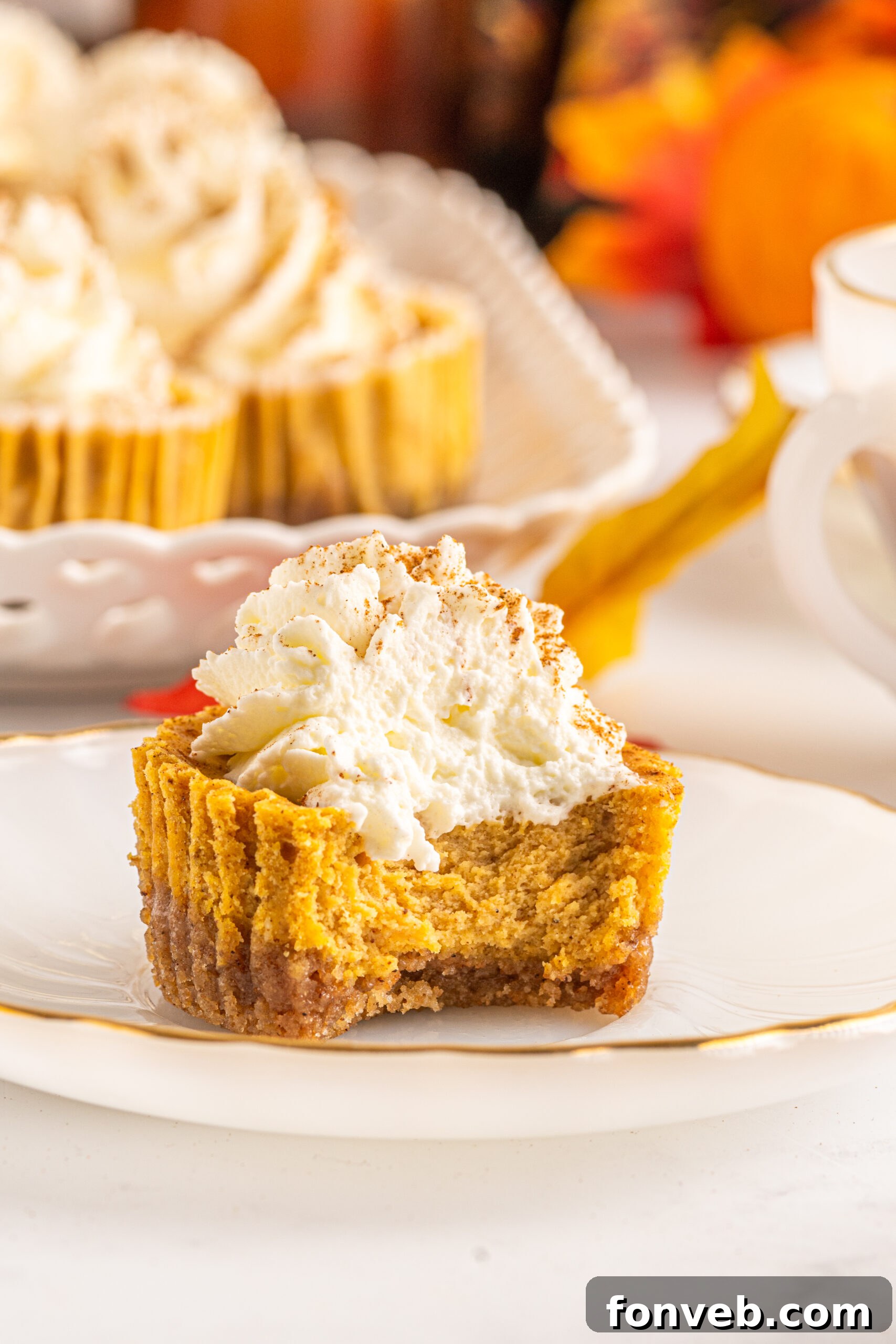 Spiced Fall Cheesecake Bites 18 Front view of a Mini Pumpkin Cheesecake with a bite removed, showing the creamy filling and crust.