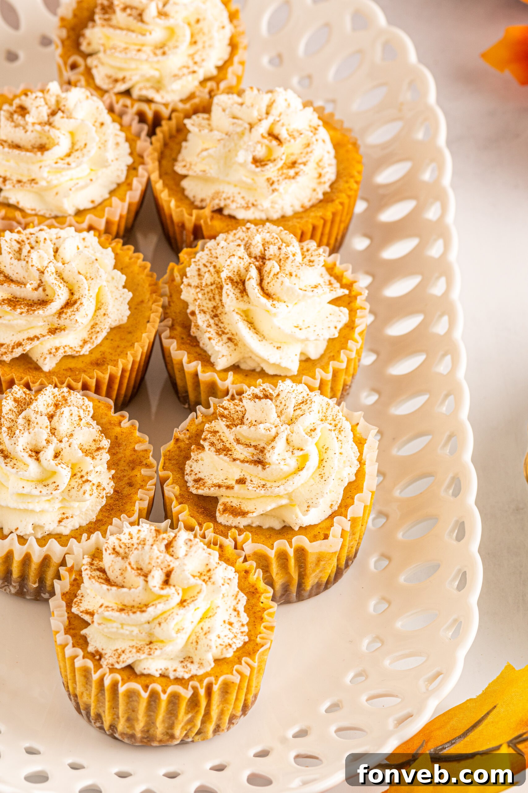 Spiced Fall Cheesecake Bites 4 Front view of several Mini Pumpkin Cheesecakes on a white serving dish, highlighting their individual perfect portions.