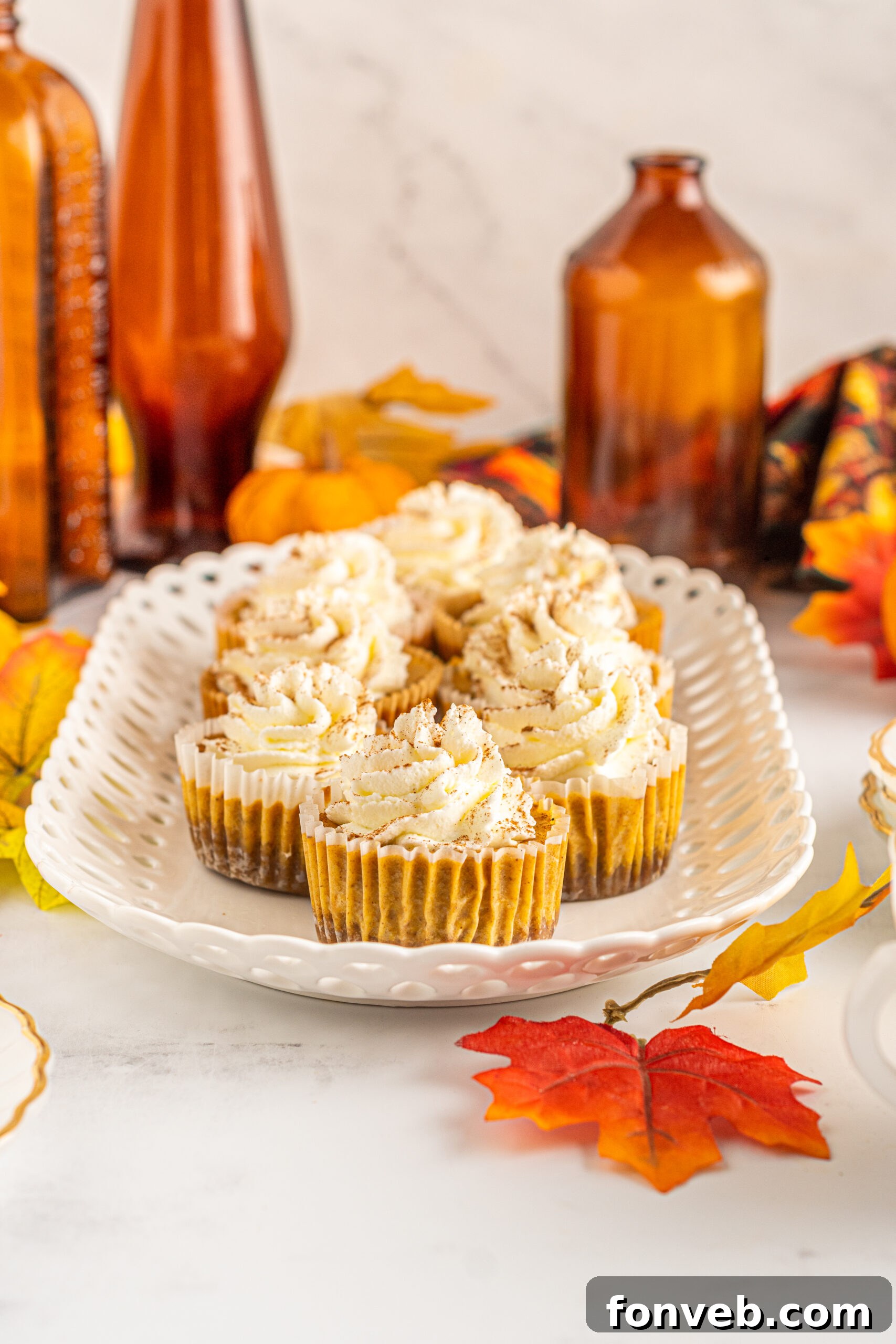 Spiced Fall Cheesecake Bites 5 Front view of Mini Pumpkin Cheesecakes arranged on a white serving dish, ready to be enjoyed.