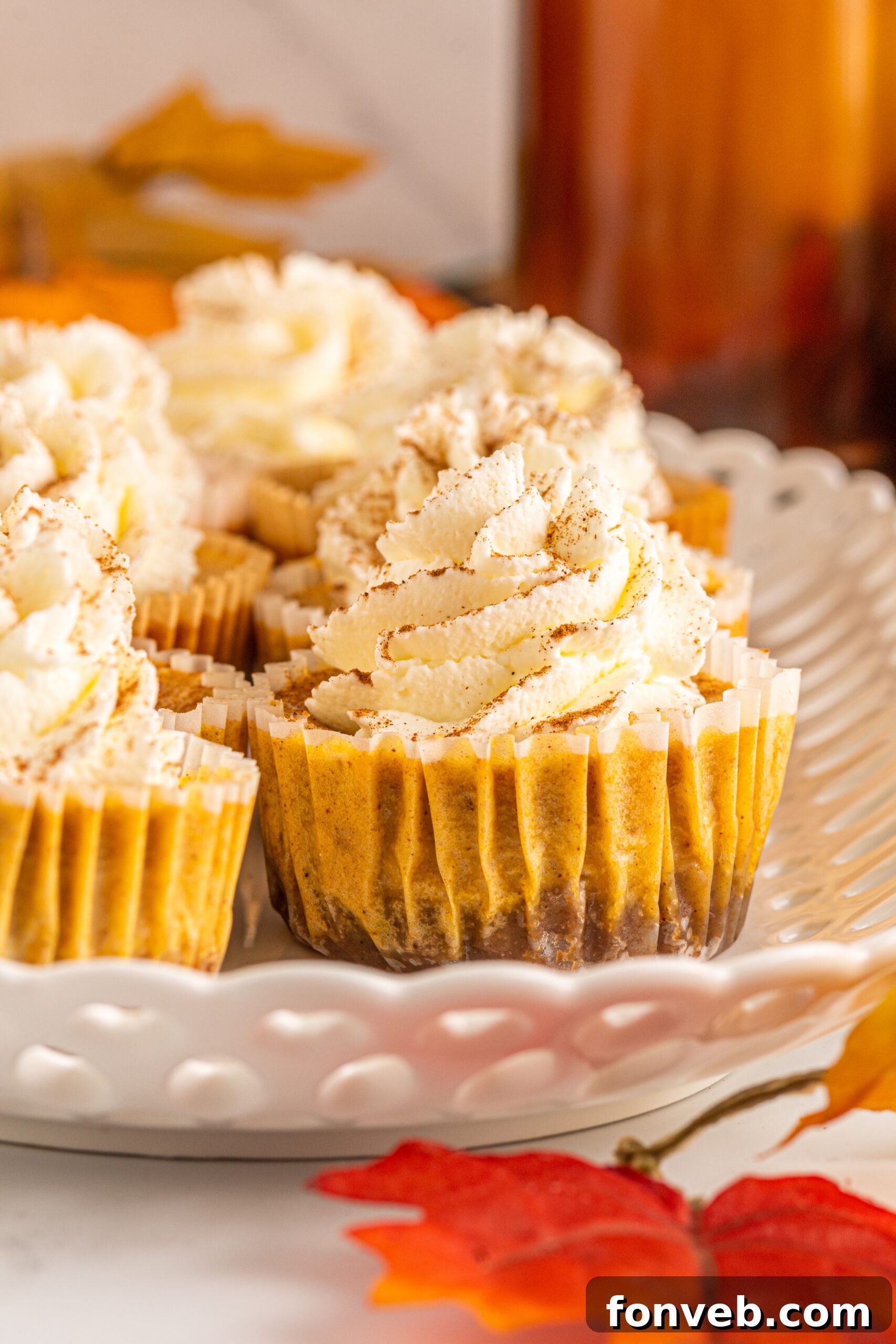 Spiced Fall Cheesecake Bites 6 Close up view of two Mini Pumpkin Cheesecakes on a white serving dish, showing the smooth texture of the filling.
