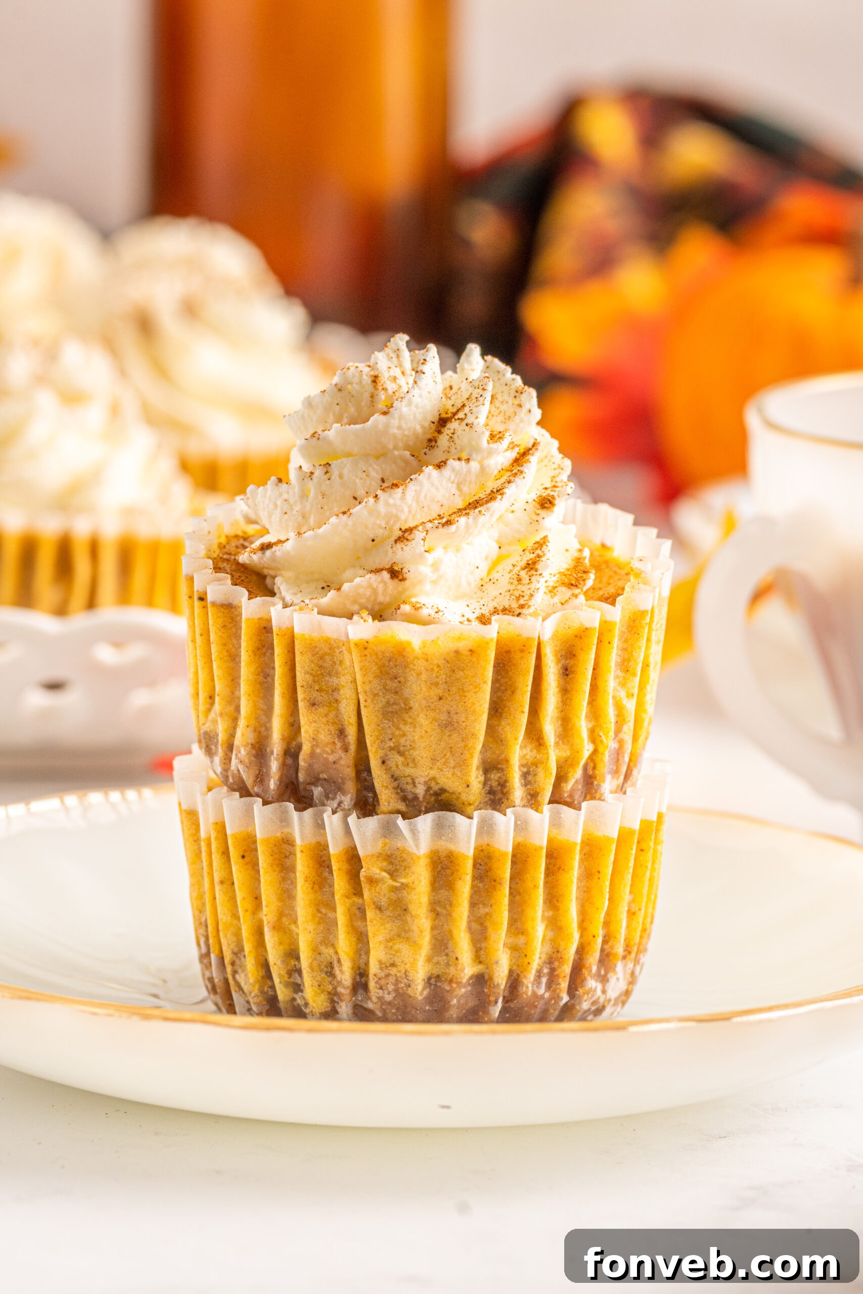 Spiced Fall Cheesecake Bites 9 Front view of two perfectly stacked Mini Pumpkin Cheesecakes on a white dish, garnished for serving.