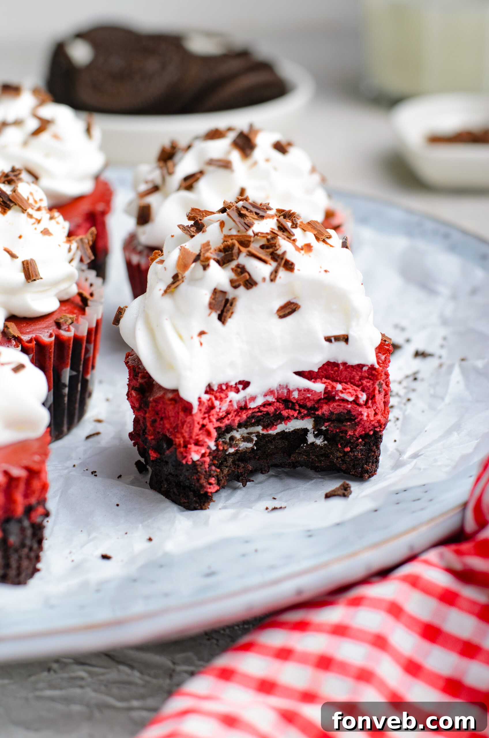 Ruby Red Oreo Cheesecake Gems 17 Front view of a Mini Red Velvet Oreo Cheesecake with a bite removed.