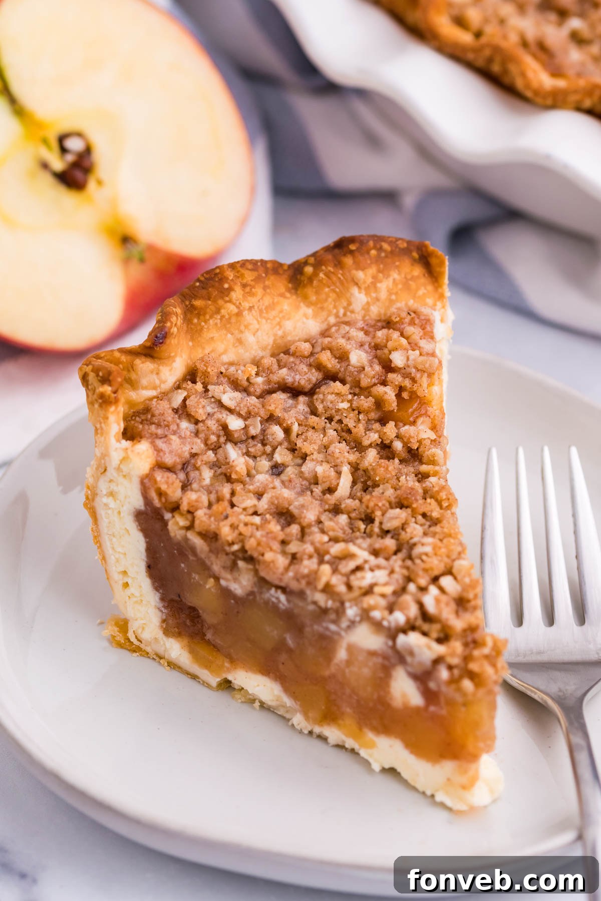 Caramel Apple Crumble Cheesecake Pie 5 Close up view of a slice of Apple Crumb Cheesecake Pie on a white dish.