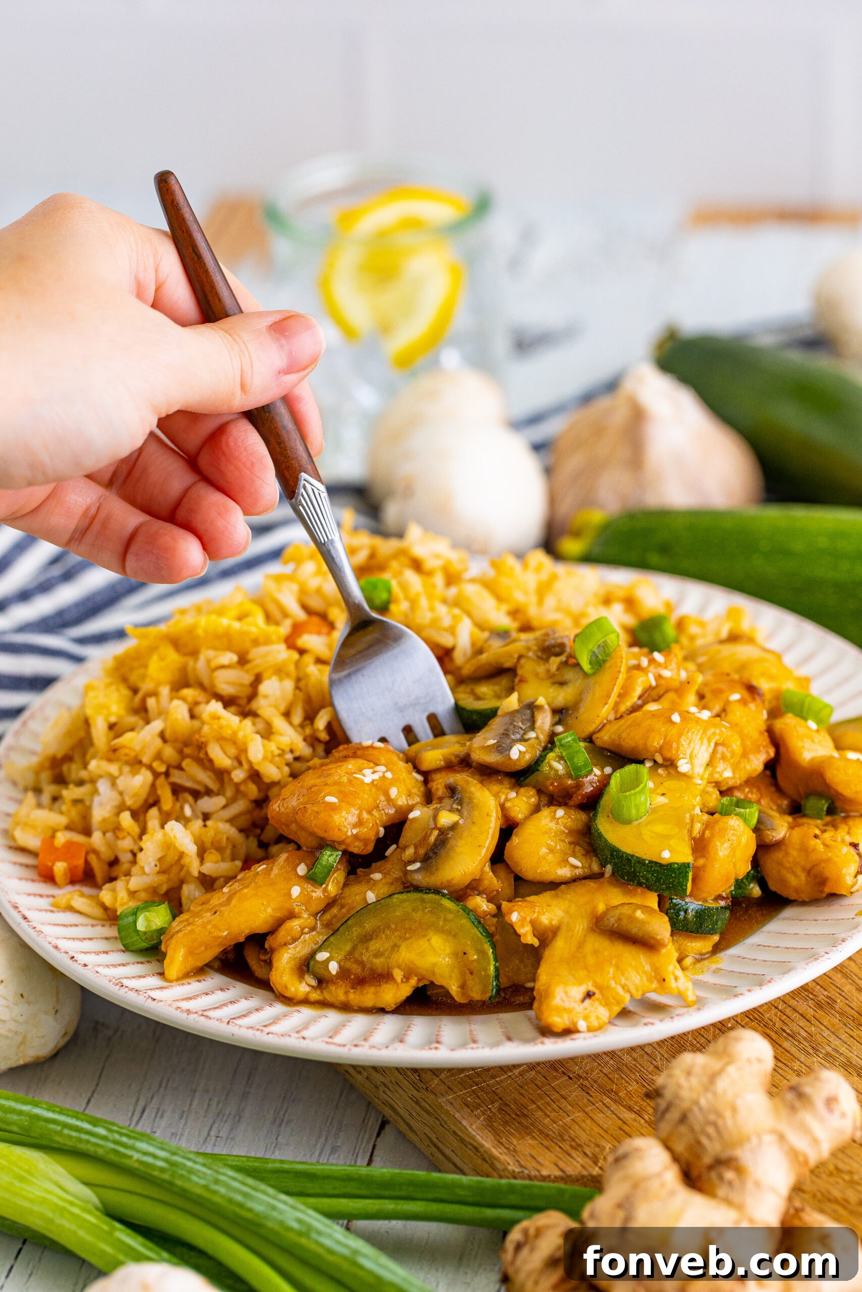 Front view of Panda Express Mushroom Chicken on a white dish served with fried rice with a silver fork.