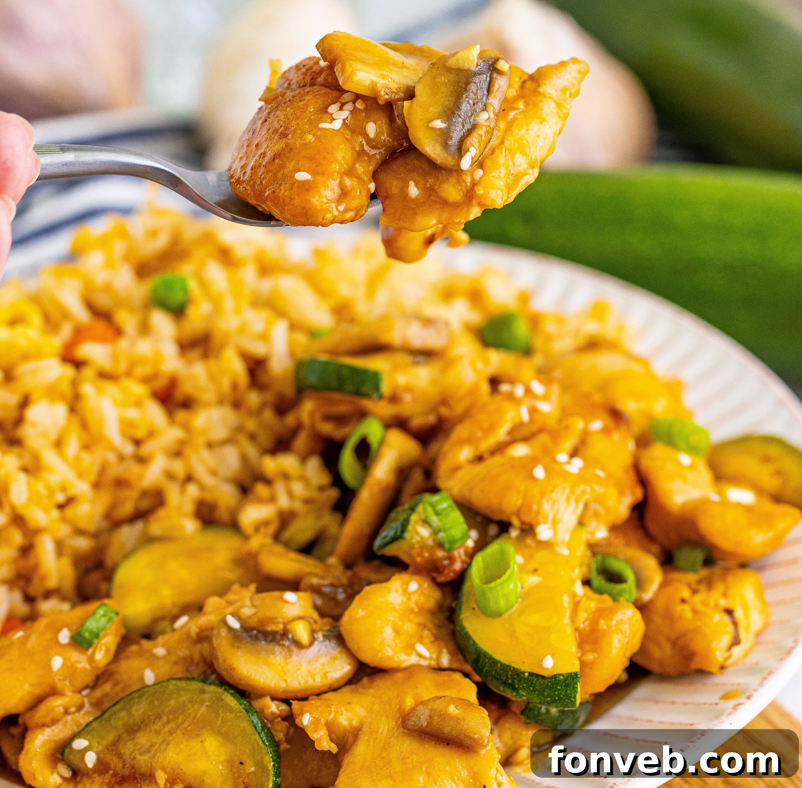 Front view of Panda Express Mushroom Chicken on a white dish served with fried rice with a spoon lifting up a bite