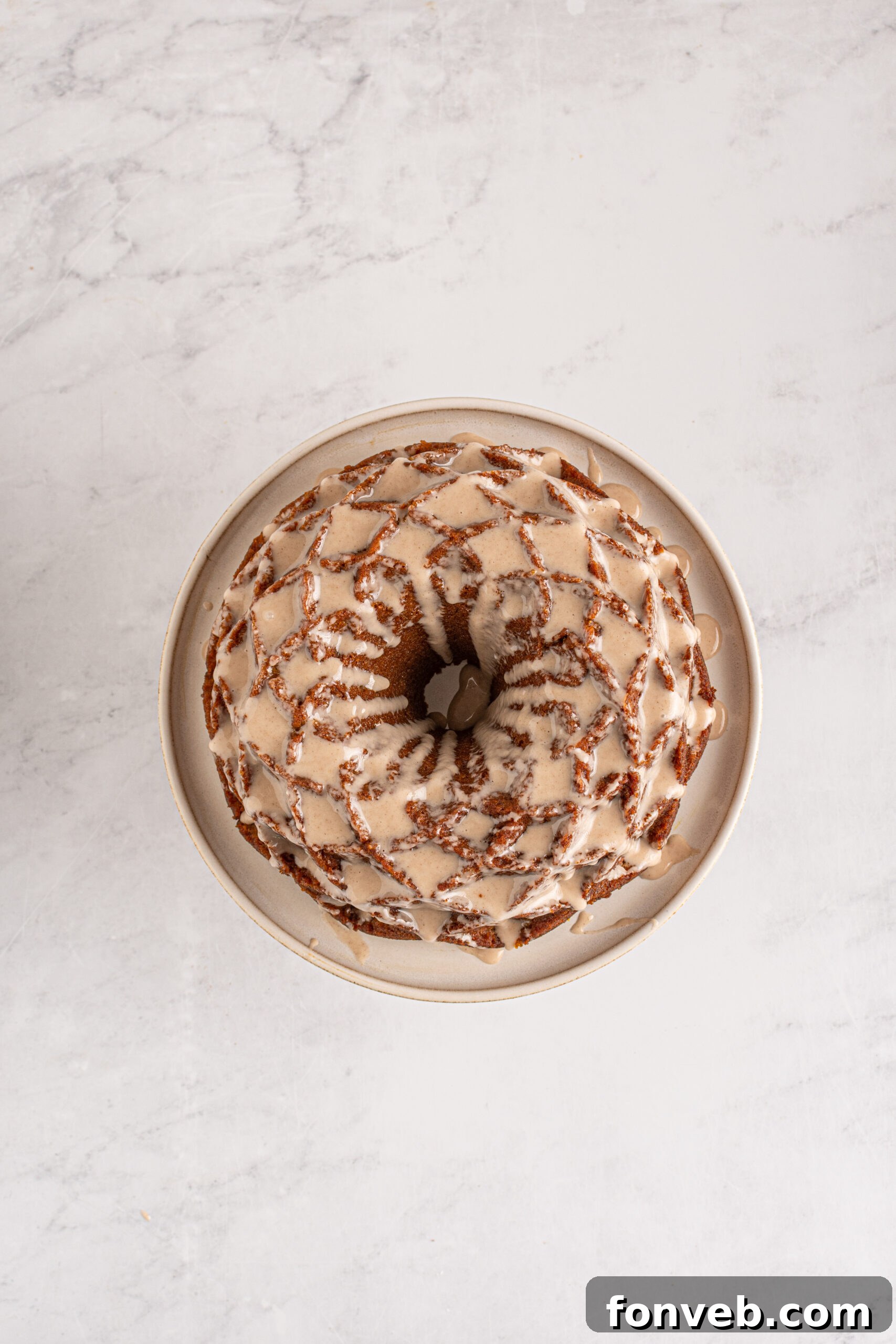 Harvest Pumpkin Bundt with Sweet Cinnamon Finish 11 Overhead view of a beautiful Pumpkin Bundt Cake with glaze drizzled over it, garnished with a few spices.