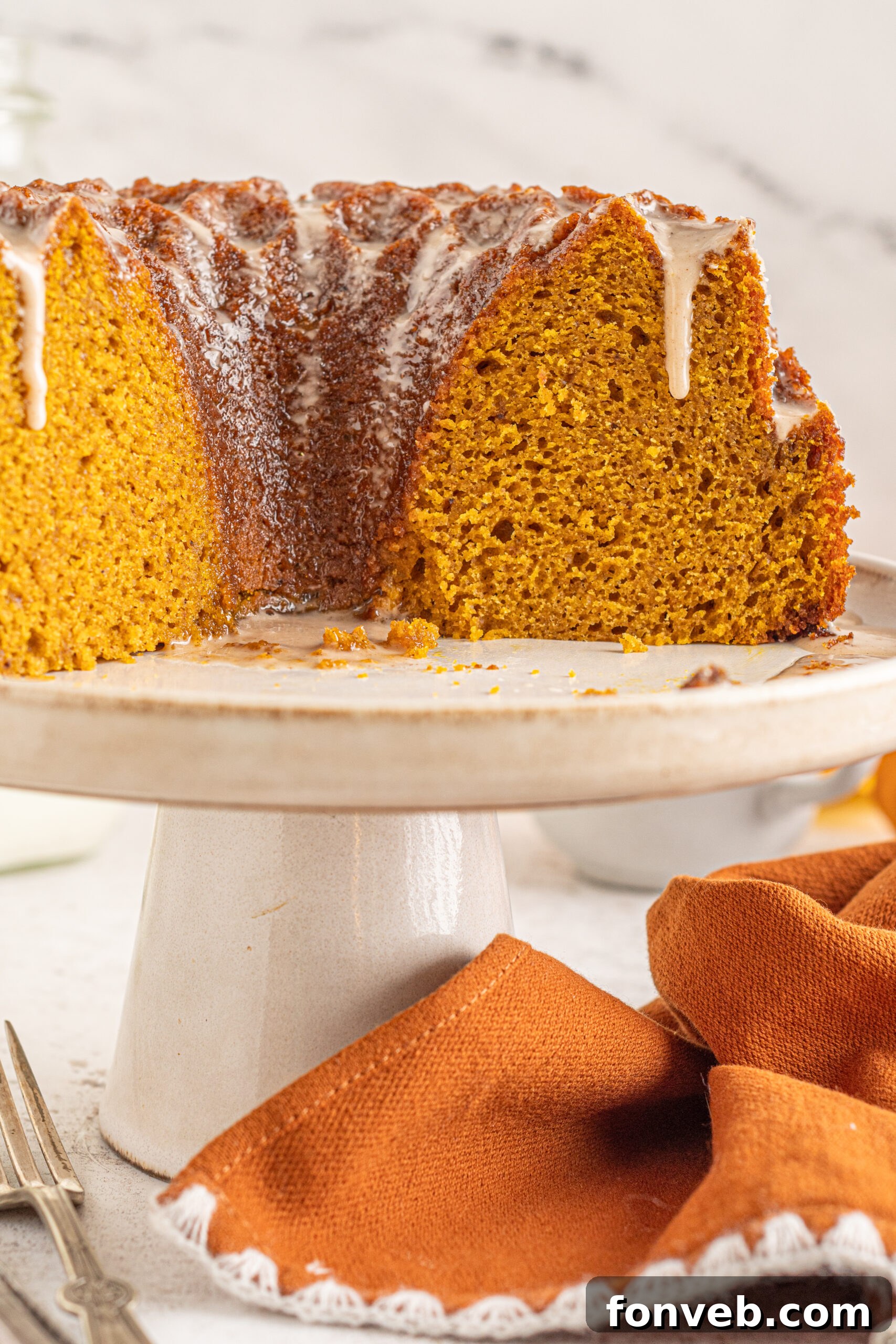 Harvest Pumpkin Bundt with Sweet Cinnamon Finish 13 Font view of Pumpkin Bundt Cake with Cinnamon Sugar Glaze with slices removed on a cake stand, ready to serve.