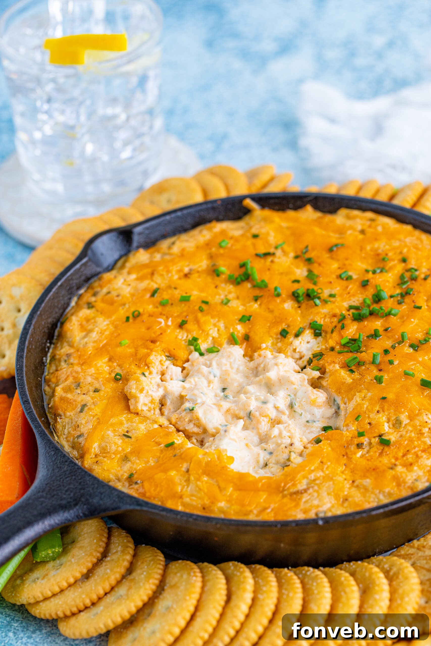 Front view of Creamy Crab Dip served in a cast iron skillet with assorted crackers and fresh vegetables.