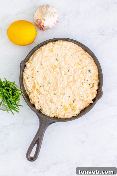A serving spoon digging into the warm, gooey crab dip, illustrating its rich consistency.