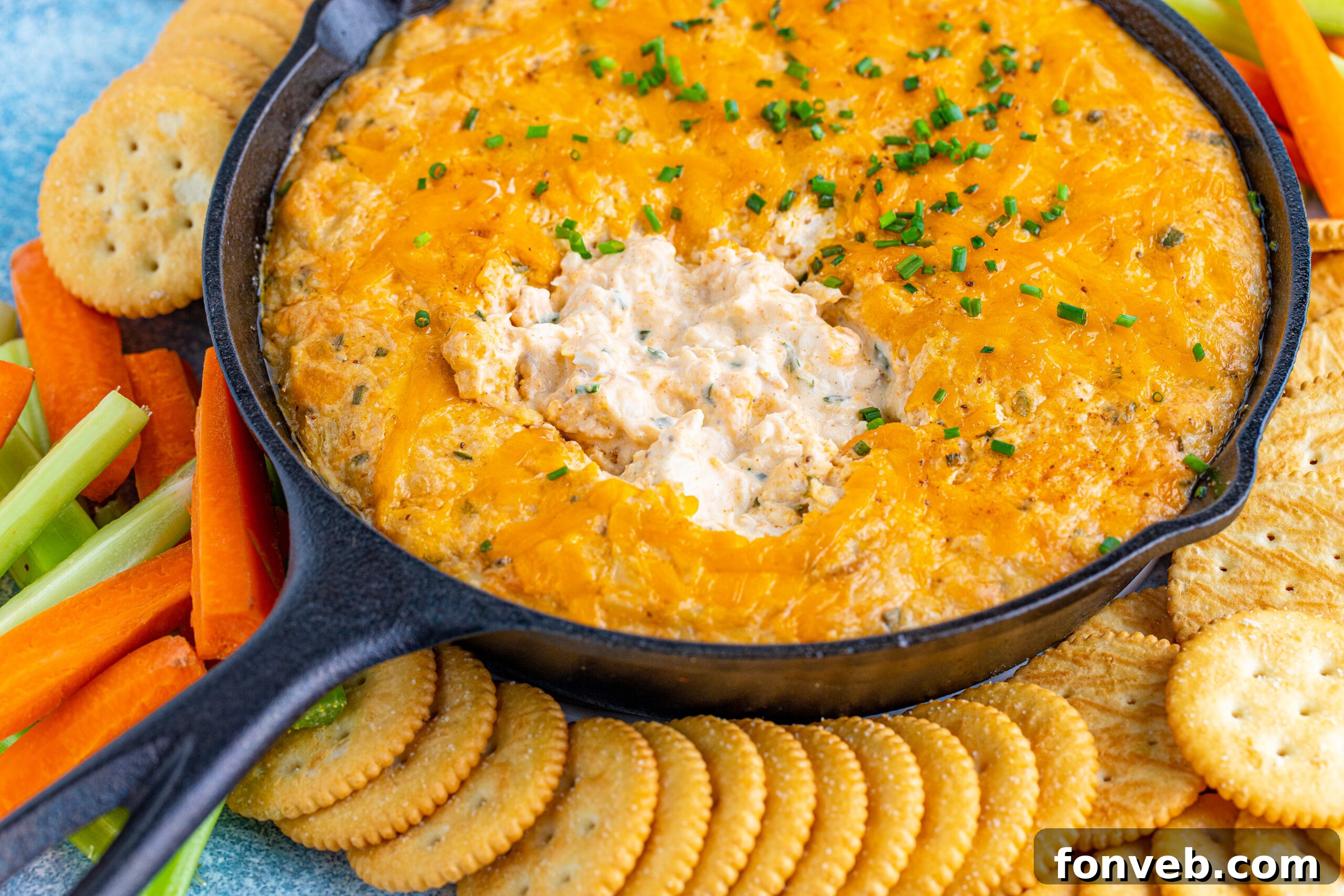Close-up front view of a bubbling Crab Dip in a cast iron skillet, ready to be served with crunchy dippers.