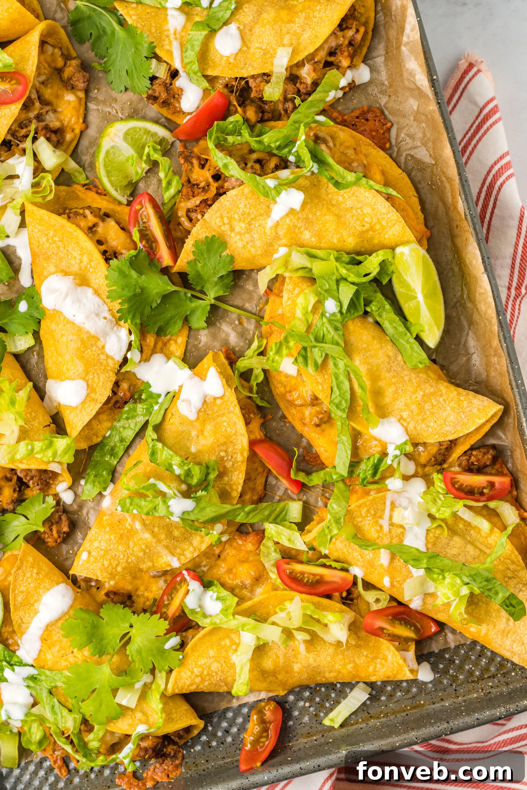 Golden Crispy Beef Tacos 2 Overhead view of Crispy Beef Tacos baking on a sheet pan, garnished with fresh cilantro and a squeeze of lime.