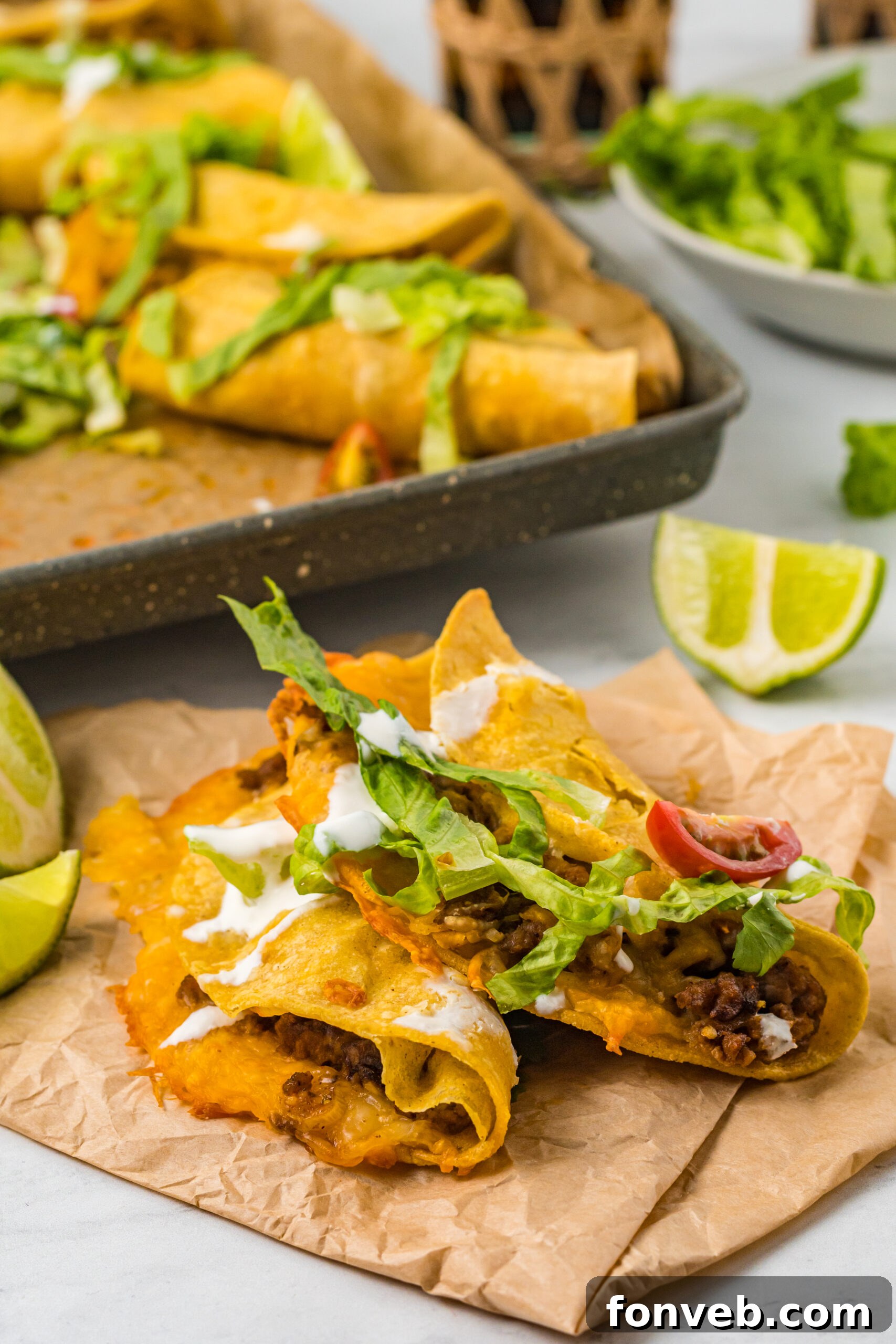 Golden Crispy Beef Tacos 11 Front view of two Crispy Beef Tacos on parchment paper, showcasing their appealing texture and readiness for toppings.