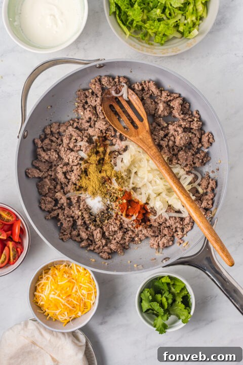 Golden Crispy Beef Tacos 13 A hand gently folding a filled corn tortilla in half, ready to be placed on a baking sheet.