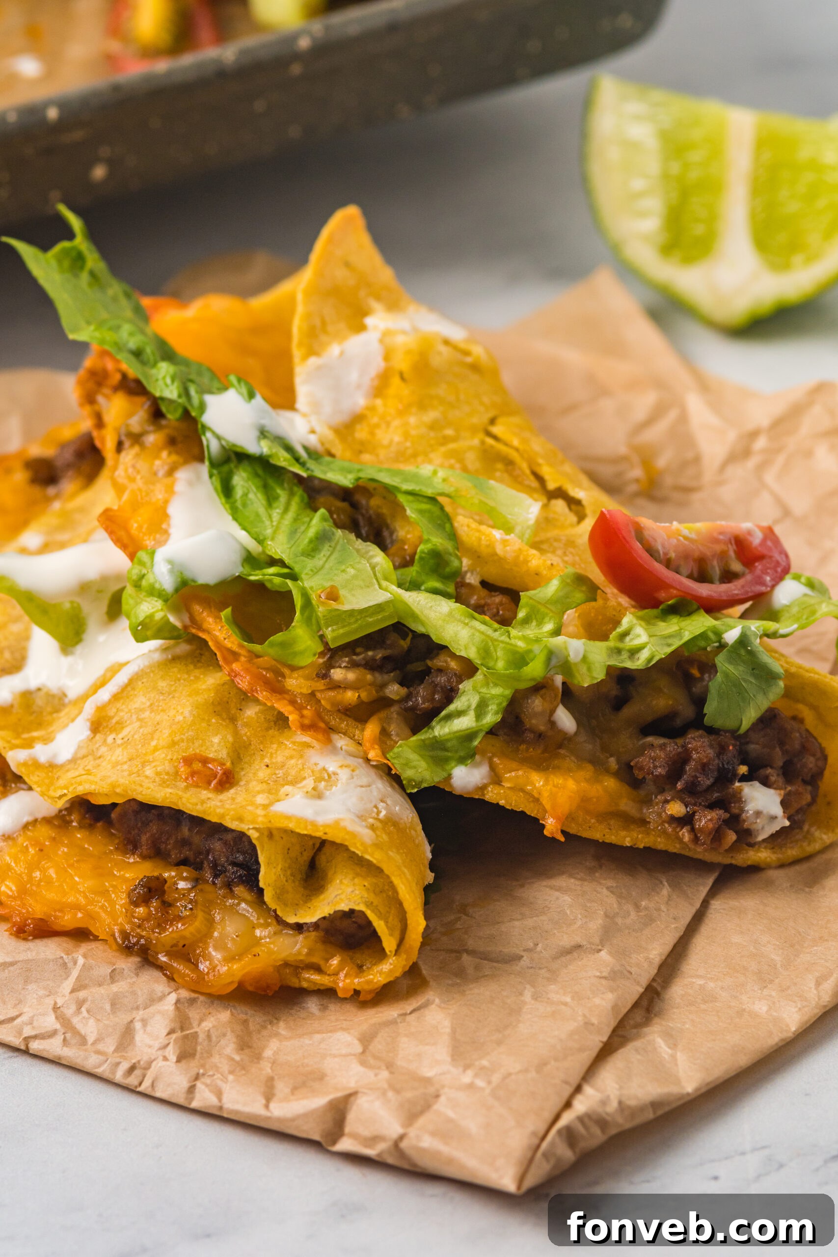 Golden Crispy Beef Tacos 10 Front view of two Crispy Beef Tacos resting on parchment paper, perfectly baked with a golden, crispy exterior.