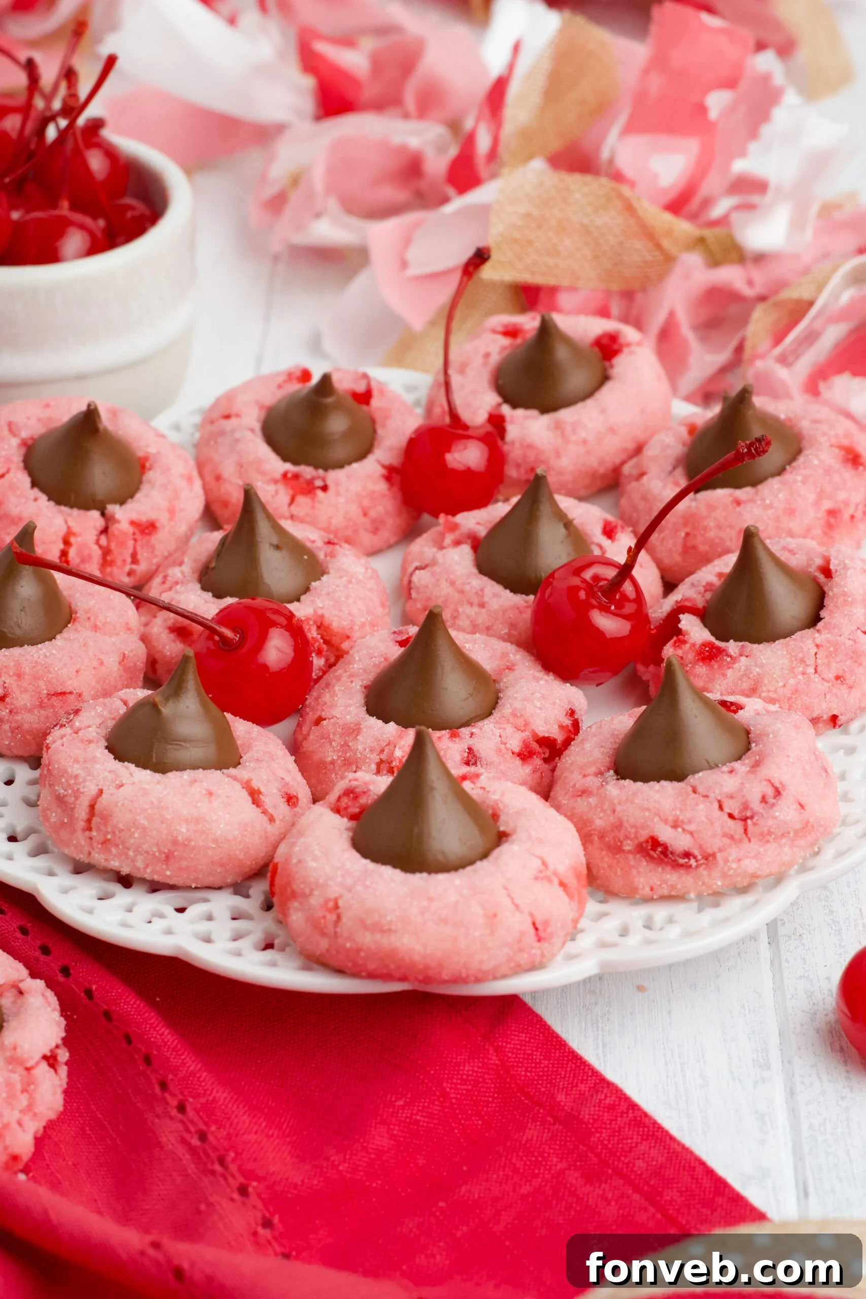 Delicate pink Cherry Blossom Cookies with a chocolate kiss in the center, arranged beautifully on a white dish.
