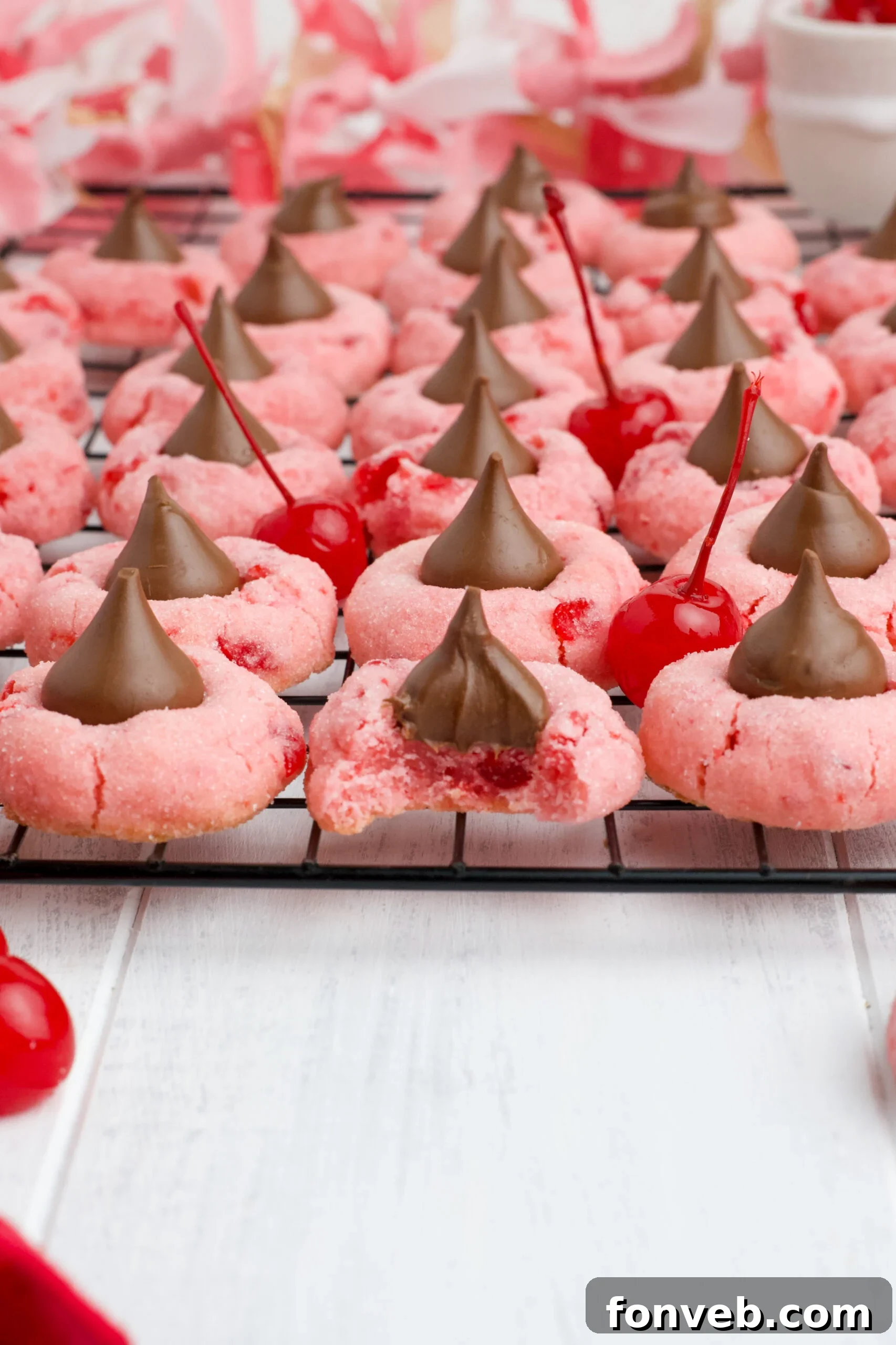 A close-up of Cherry Blossom Cookies on a black wire rack, with one cookie showing a bite taken.