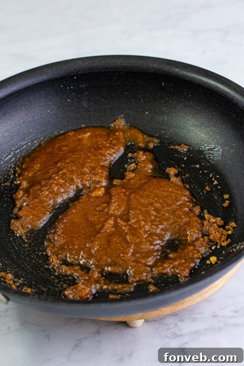 Salted butter melting in a large skillet over medium heat.