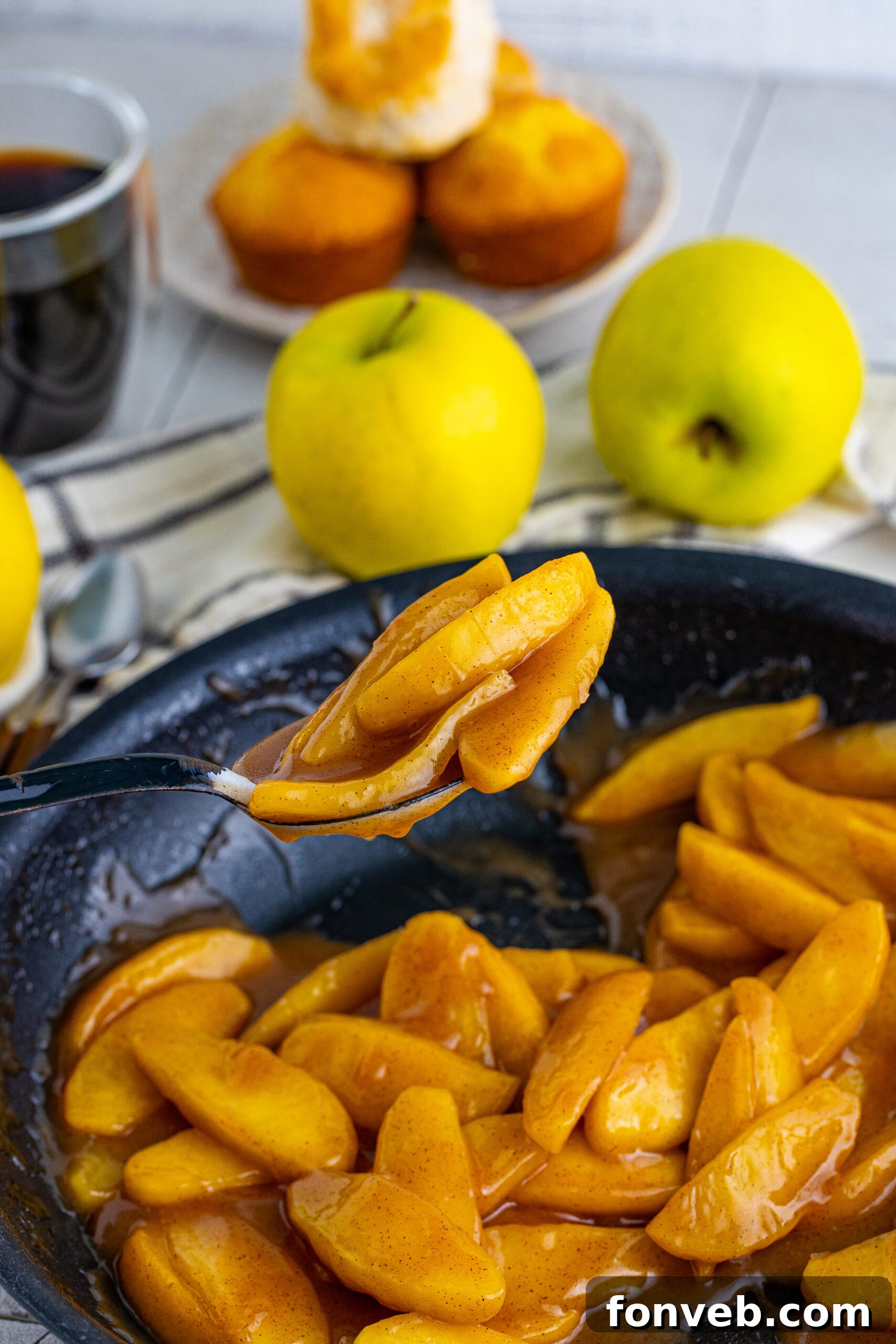 Overhead view of a black spoon holding a spoonful of Cracker Barrel Fried Apples, showcasing their perfect glaze.