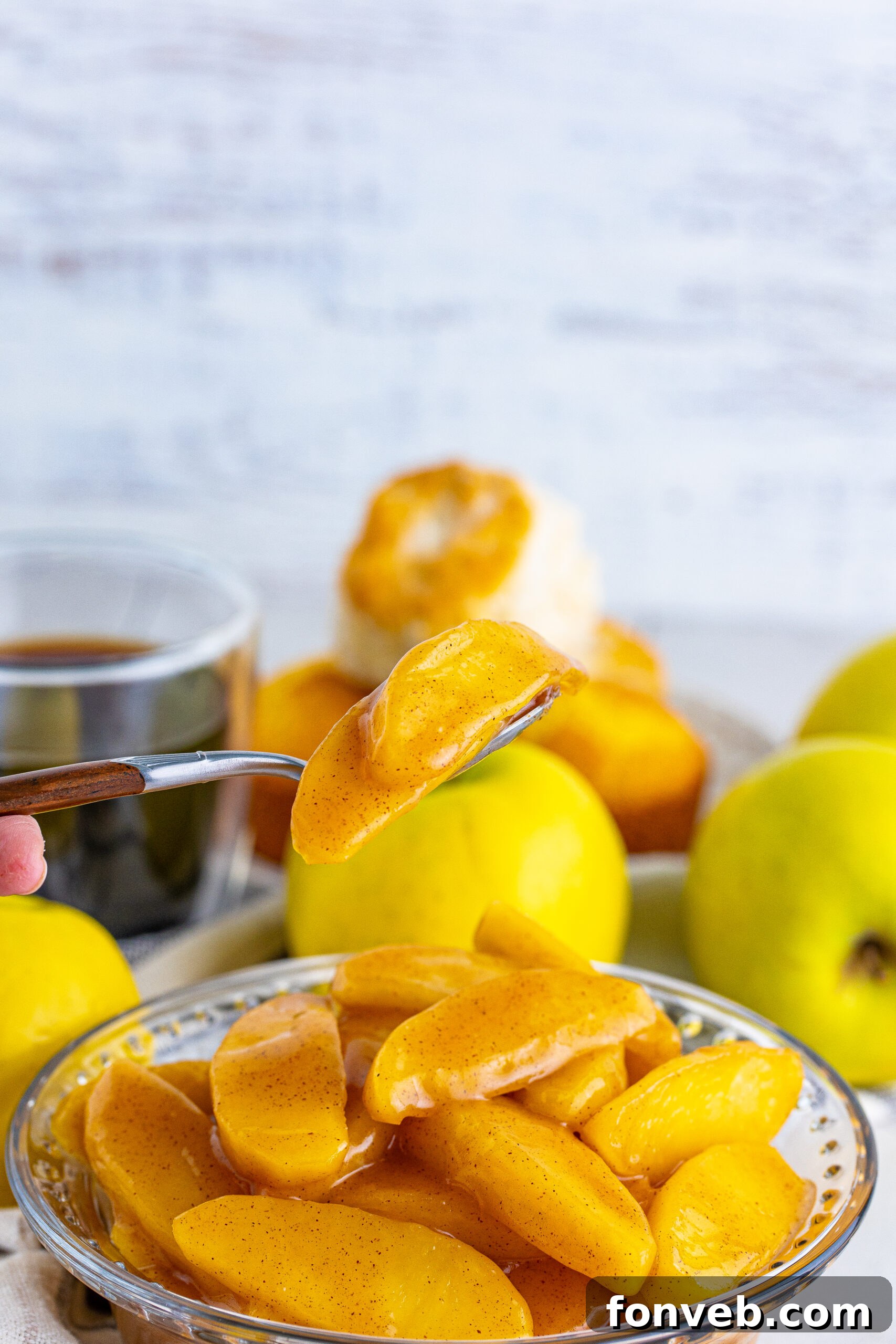Front view of Cracker Barrel Fried Apples in a clear glass bowl with a silver spoon full of fried apples, emphasizing texture and glaze.