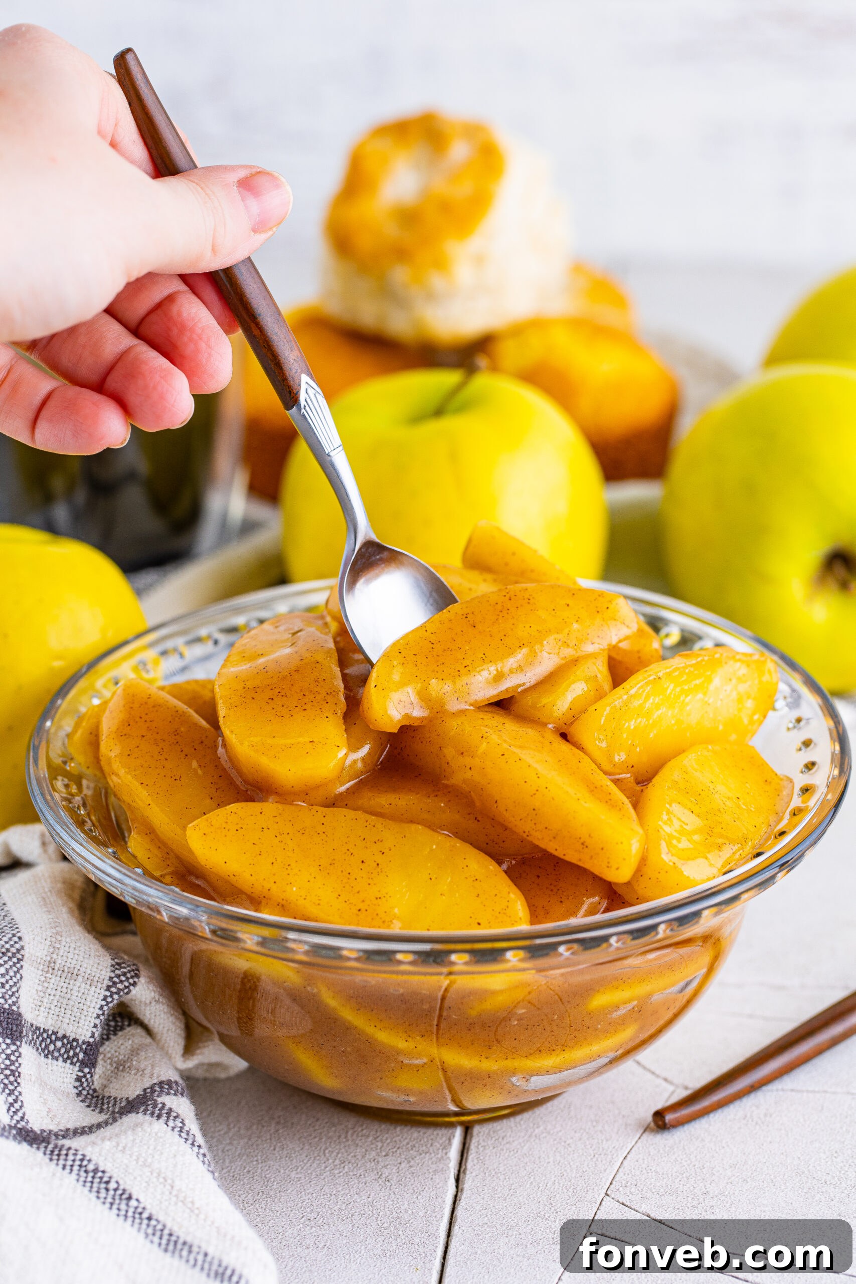 Front view of Cracker Barrel Fried Apples in a clear glass bowl with a silver spoon, showing off the syrupy sauce.