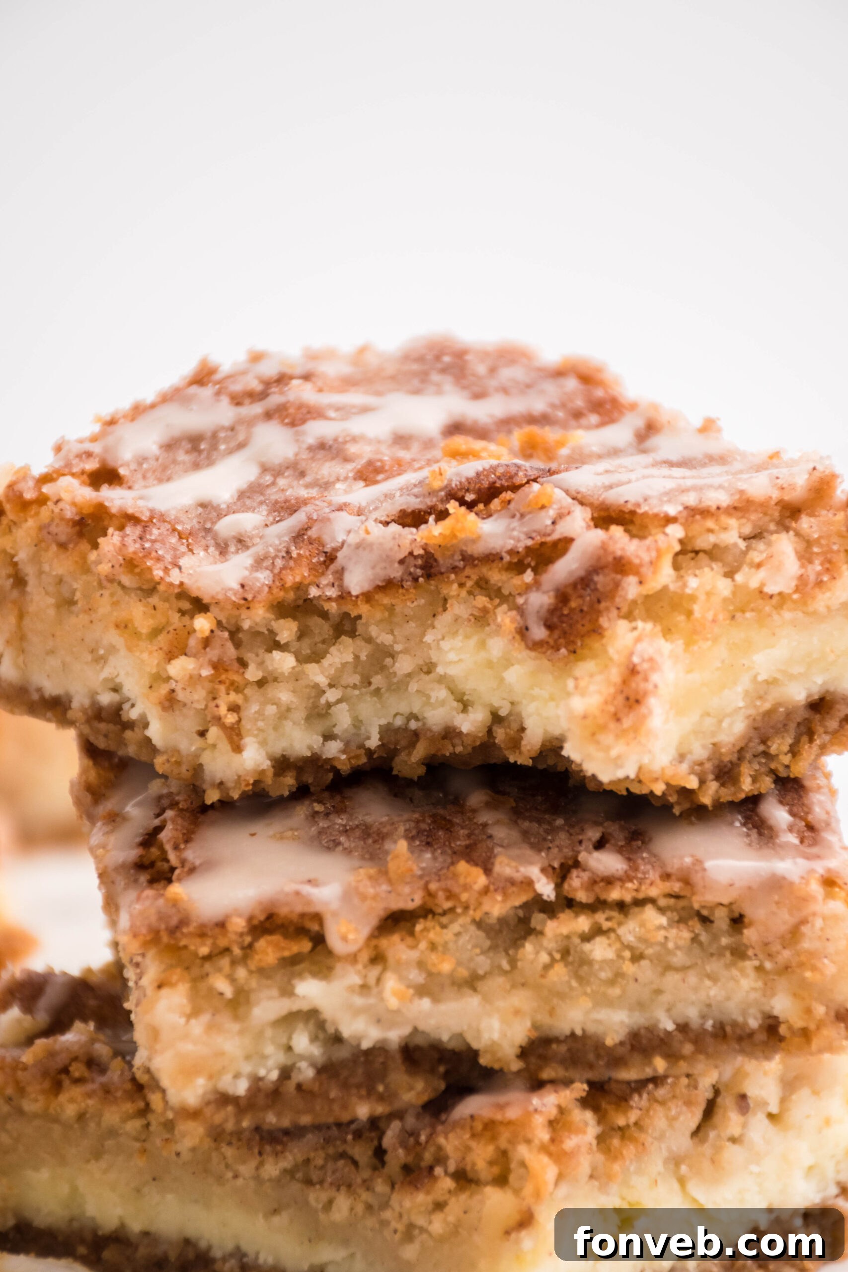 Front view of three Snickerdoodle Cheesecake Bars stacked with a bite removed from the top bar, displaying the multi-layered texture.