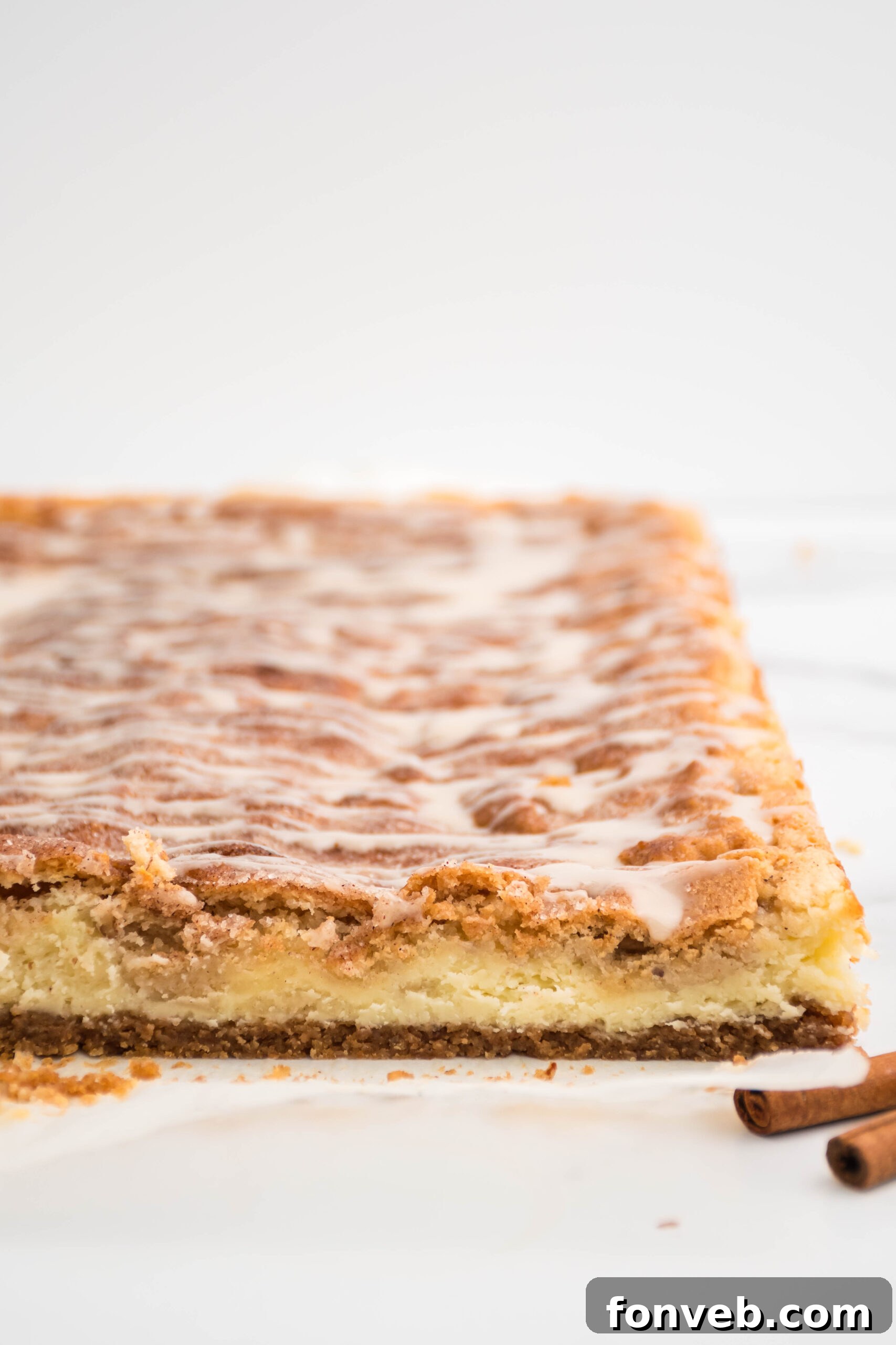 Front view of golden-brown Snickerdoodle Cheesecake Bars uncut in a pan, highlighting the top crust.
