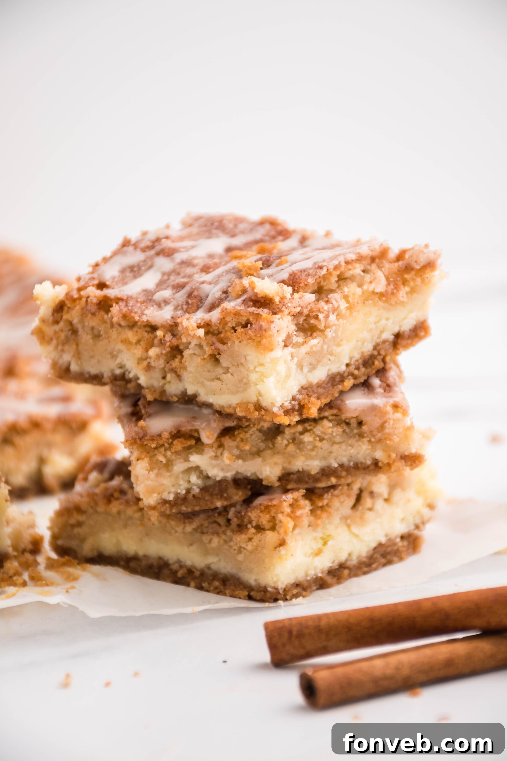 Front view of three Snickerdoodle Cheesecake Bars stacked on a white plate.
