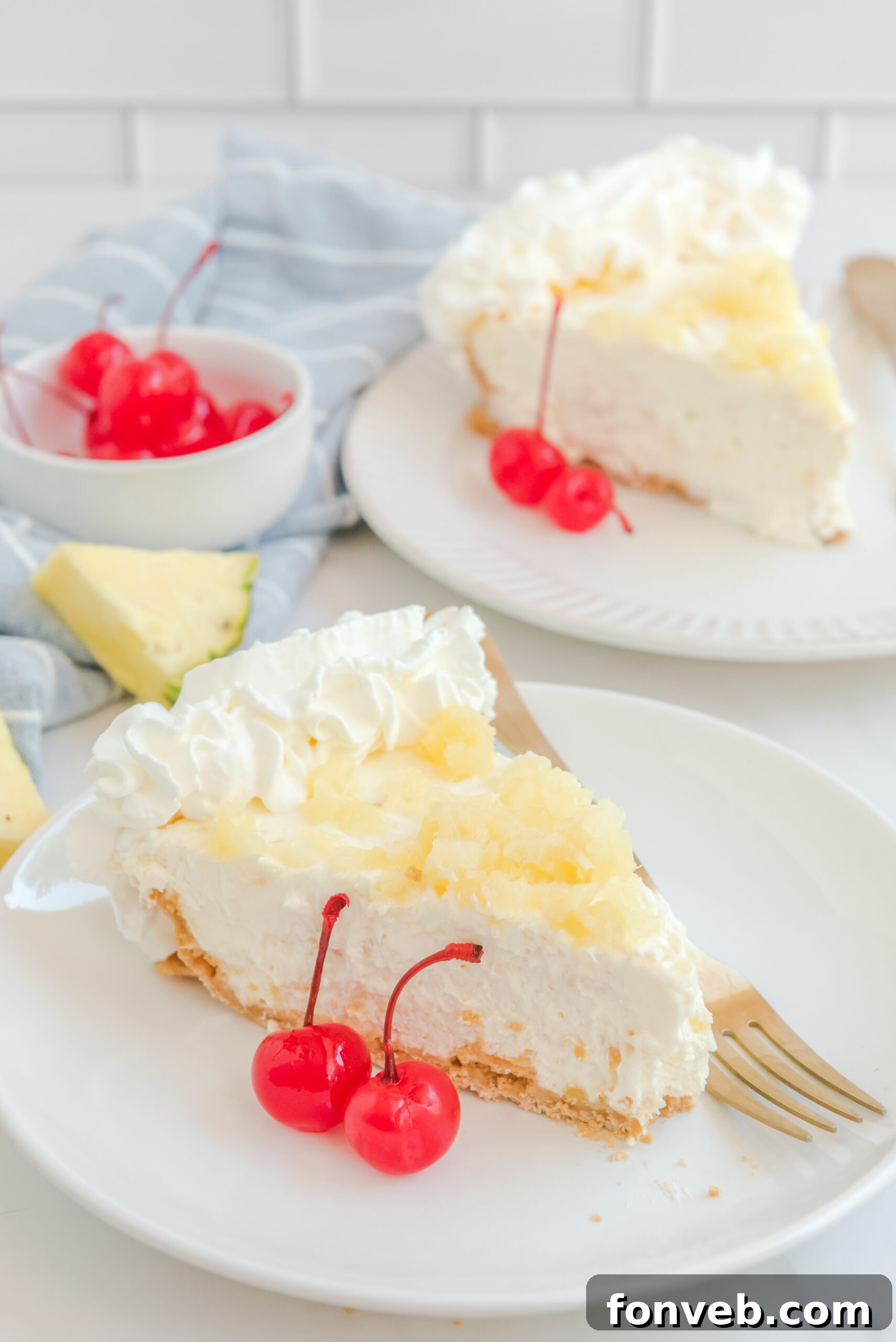 No Bake Pineapple Cheesecake Pie on a white plate with maraschino cherries next to a slice