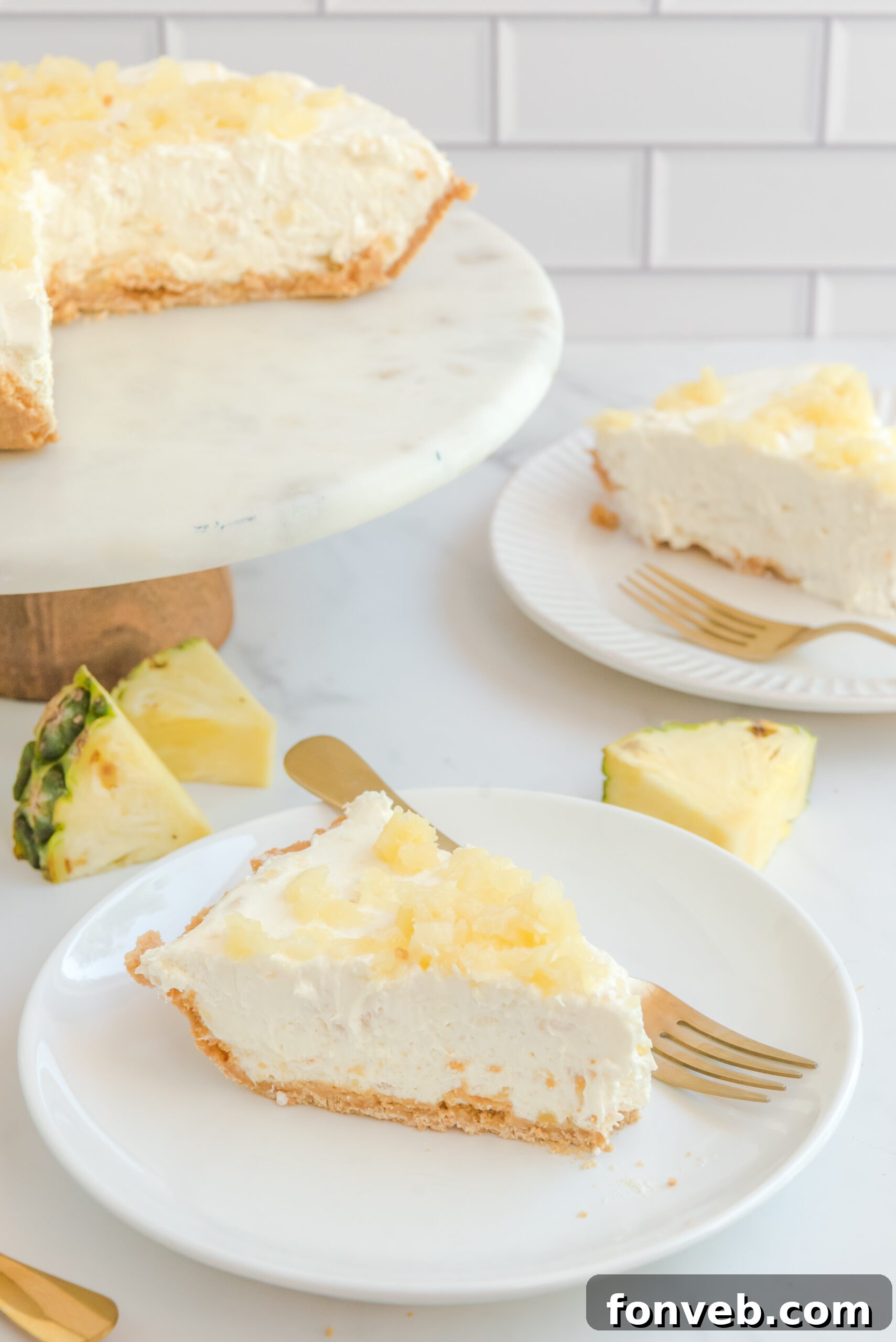 Front view of a slice of No Bake Pineapple Cheesecake on a white plate served with a gold fork.