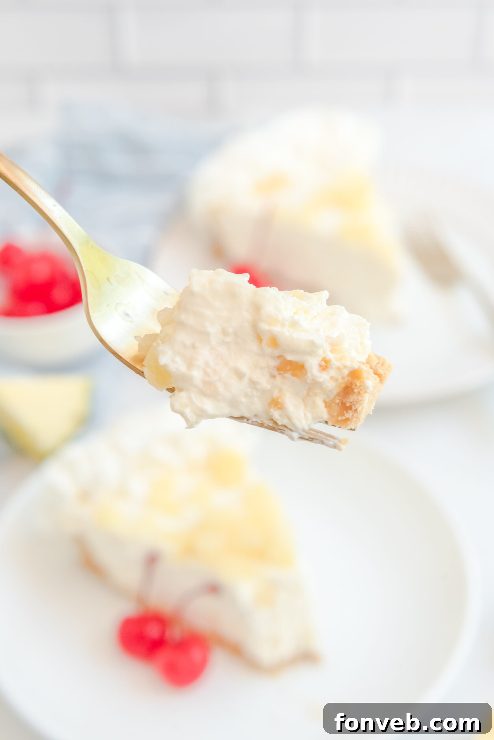 Up close view of a bite of No Bake Pineapple Cheesecake on a gold fork.