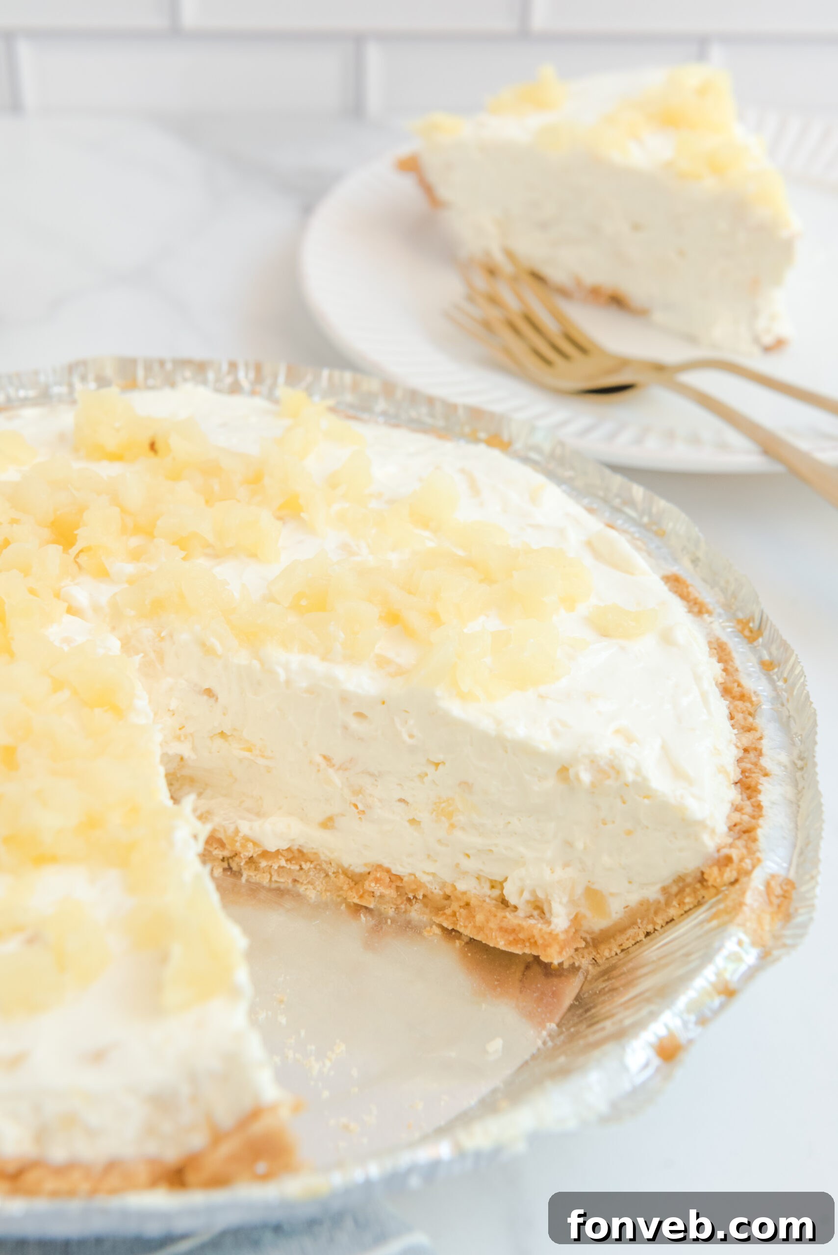 No Bake Pineapple Cheesecake Pie in a pie plate with a slice removed