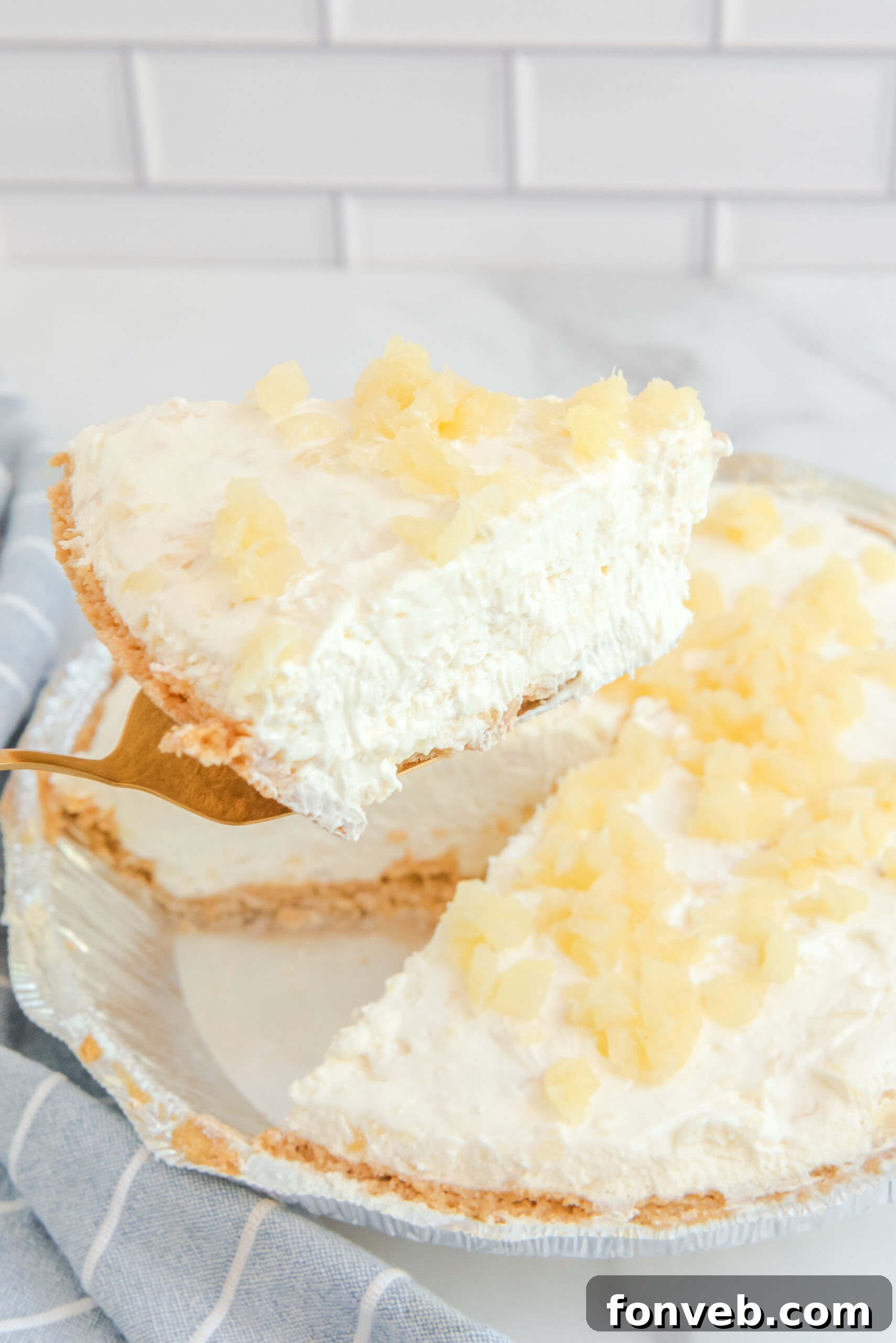 Side view of a slice of No Bake Pineapple Cheesecake on a gold cake server.