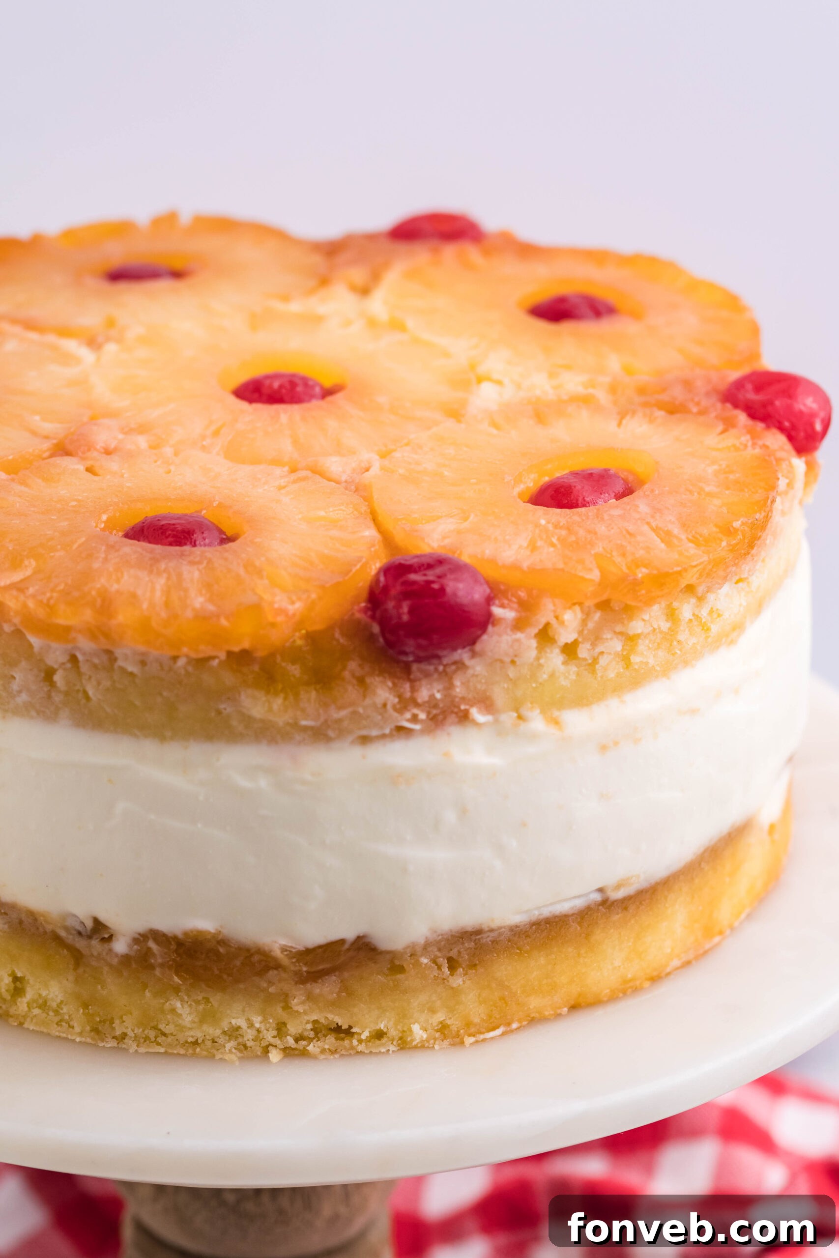 Up close view of Pineapple Upside Down Cheesecake Cake on a white and wooden cake stand.
