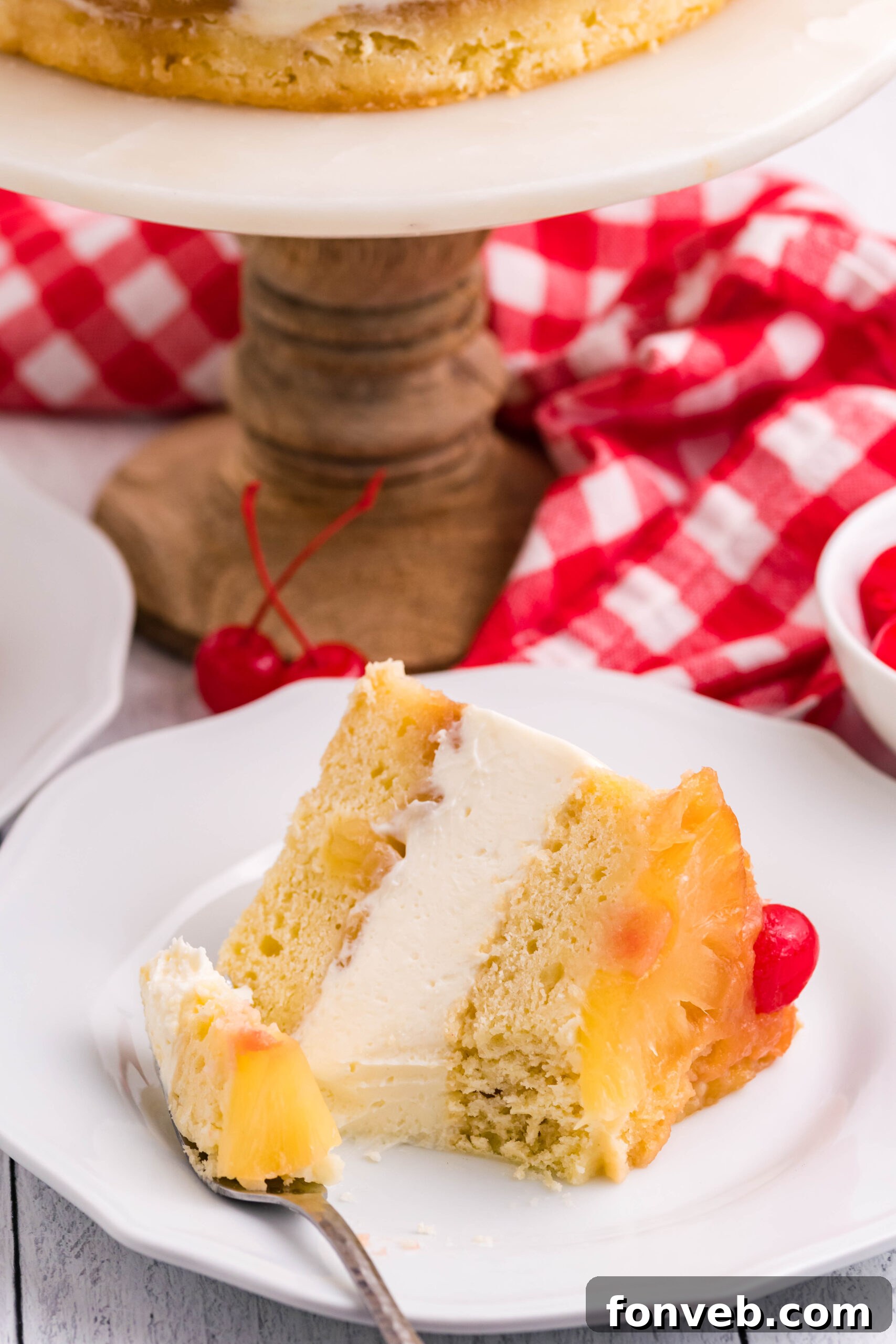 Front view of a slice of Pineapple Upside Down Cheesecake Cake with a bite removed by a silver fork.