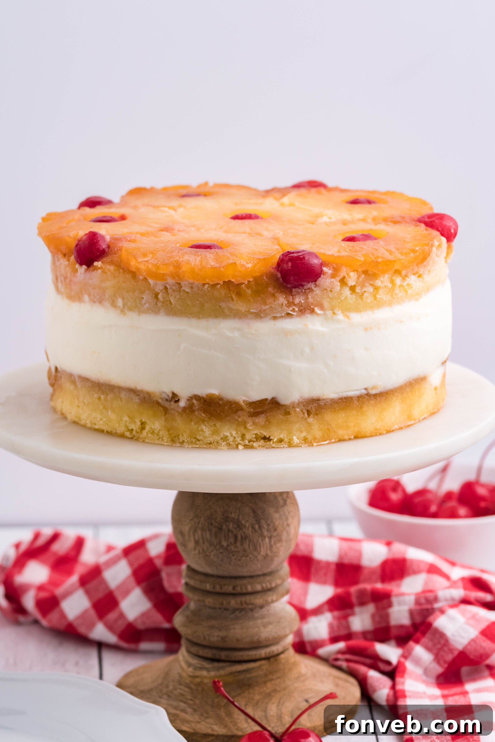 Front view of Pineapple Upside Down Cheesecake Cake on a white and wooden cake stand.