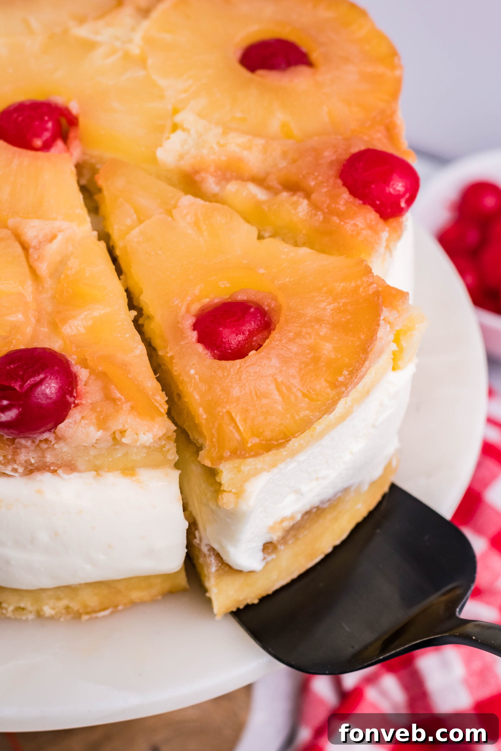 Up close view of a slice of Pineapple Upside Down Cheesecake Cake being removed with a black cake server.
