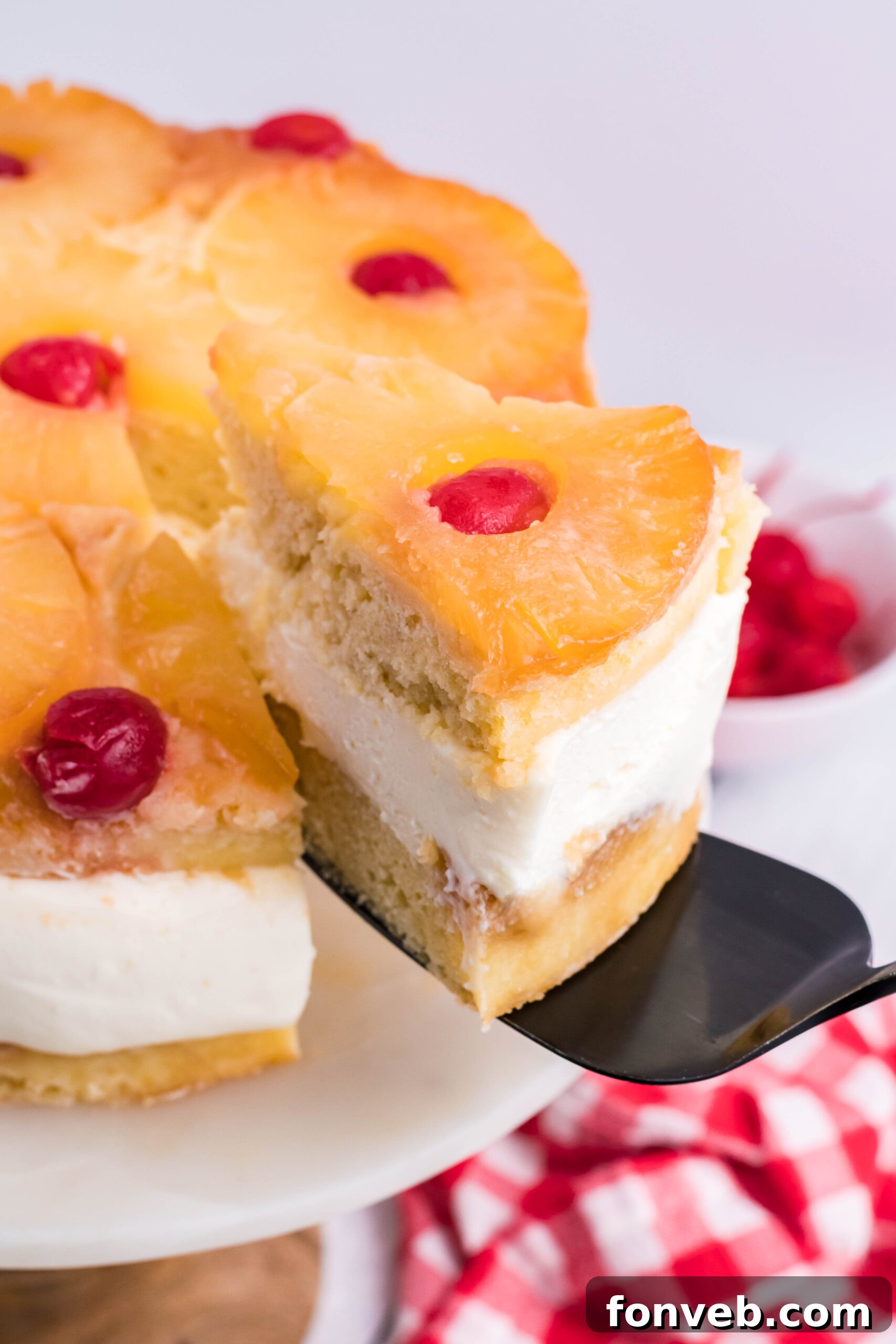 Up close view of a slice of Pineapple Upside Down Cheesecake Cake being removed with a black cake server.