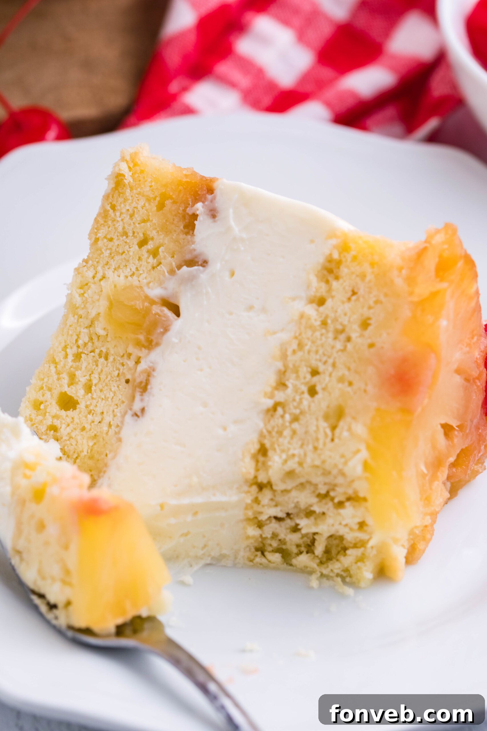 Up close view of a slice of Pineapple Upside Down Cheesecake Cake with a bite removed by a silver fork.