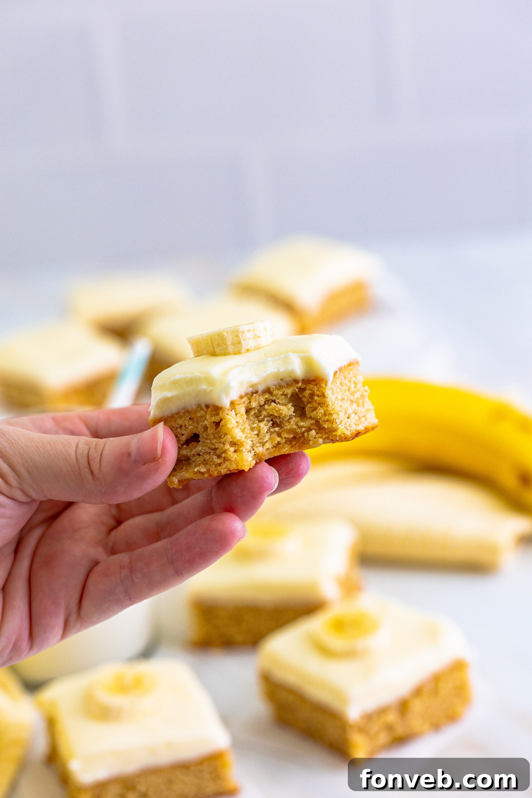 Front view of a Banana Brownie being held, showing a bite removed to reveal its soft interior.