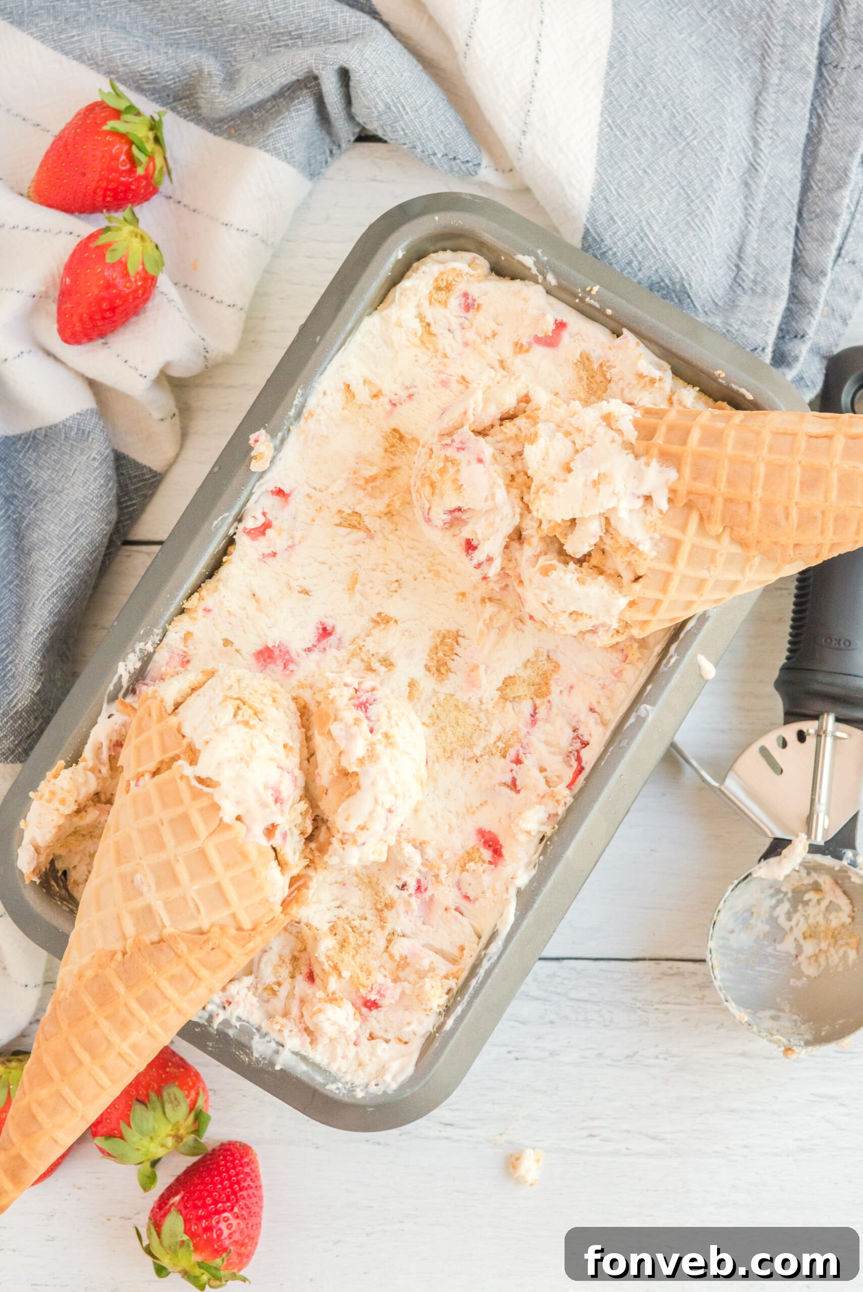 Frozen Strawberry Cheesecake Dream 11 Overhead view of a pan full of Strawberry Cheesecake Ice Cream with two waffle cones laying on top.
