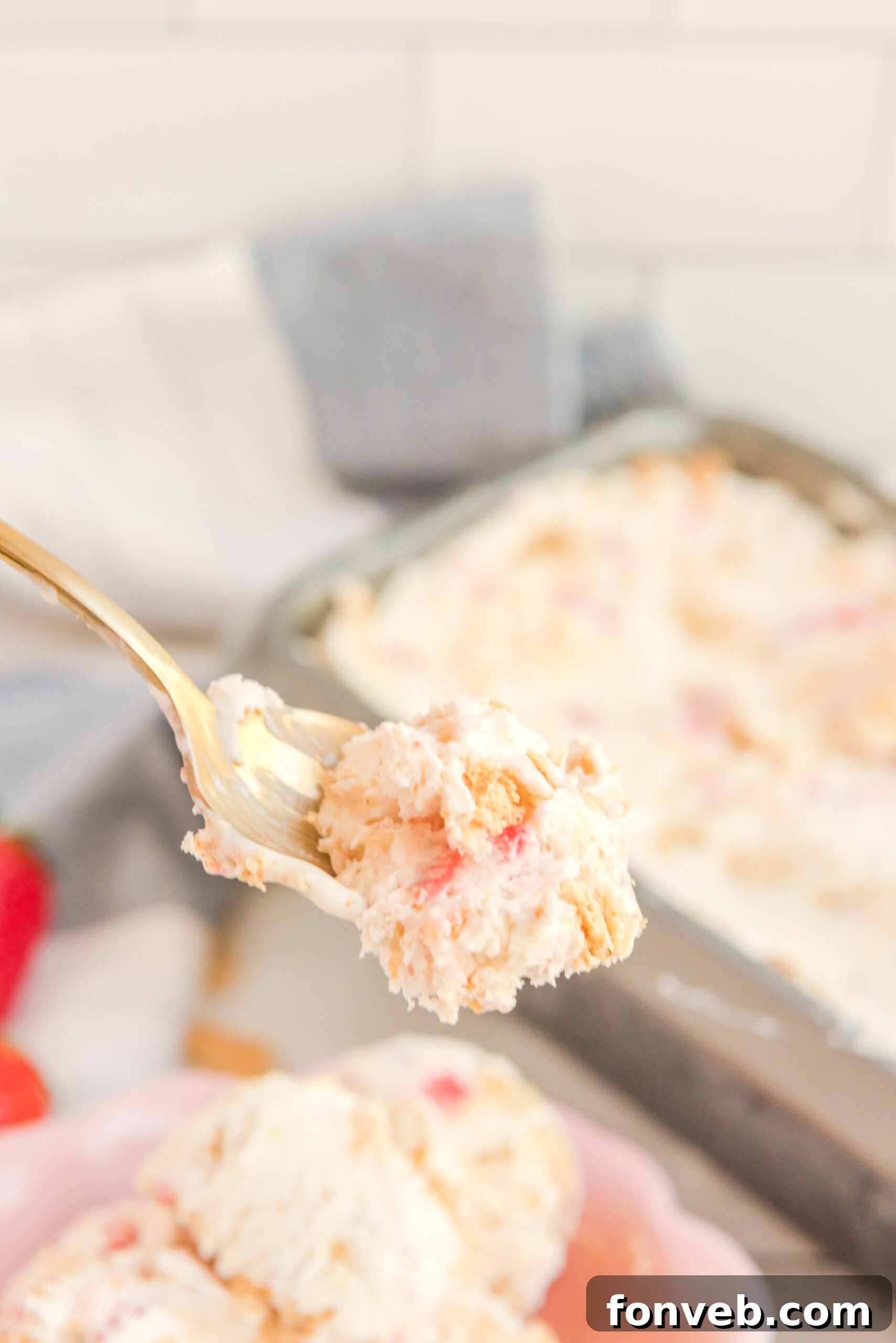 Frozen Strawberry Cheesecake Dream 14 Front view of a bite of Strawberry Cheesecake Ice Cream on a gold spoon.