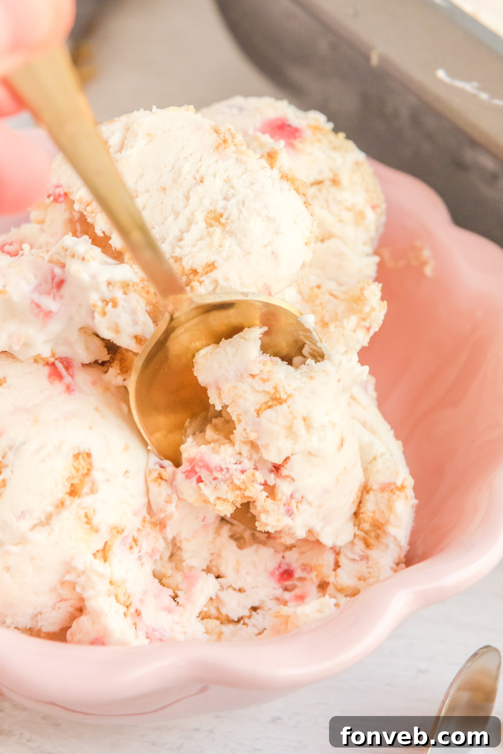 Frozen Strawberry Cheesecake Dream 22 Close up view of a gold spoon removing a bite of Strawberry Cheesecake Ice Cream.